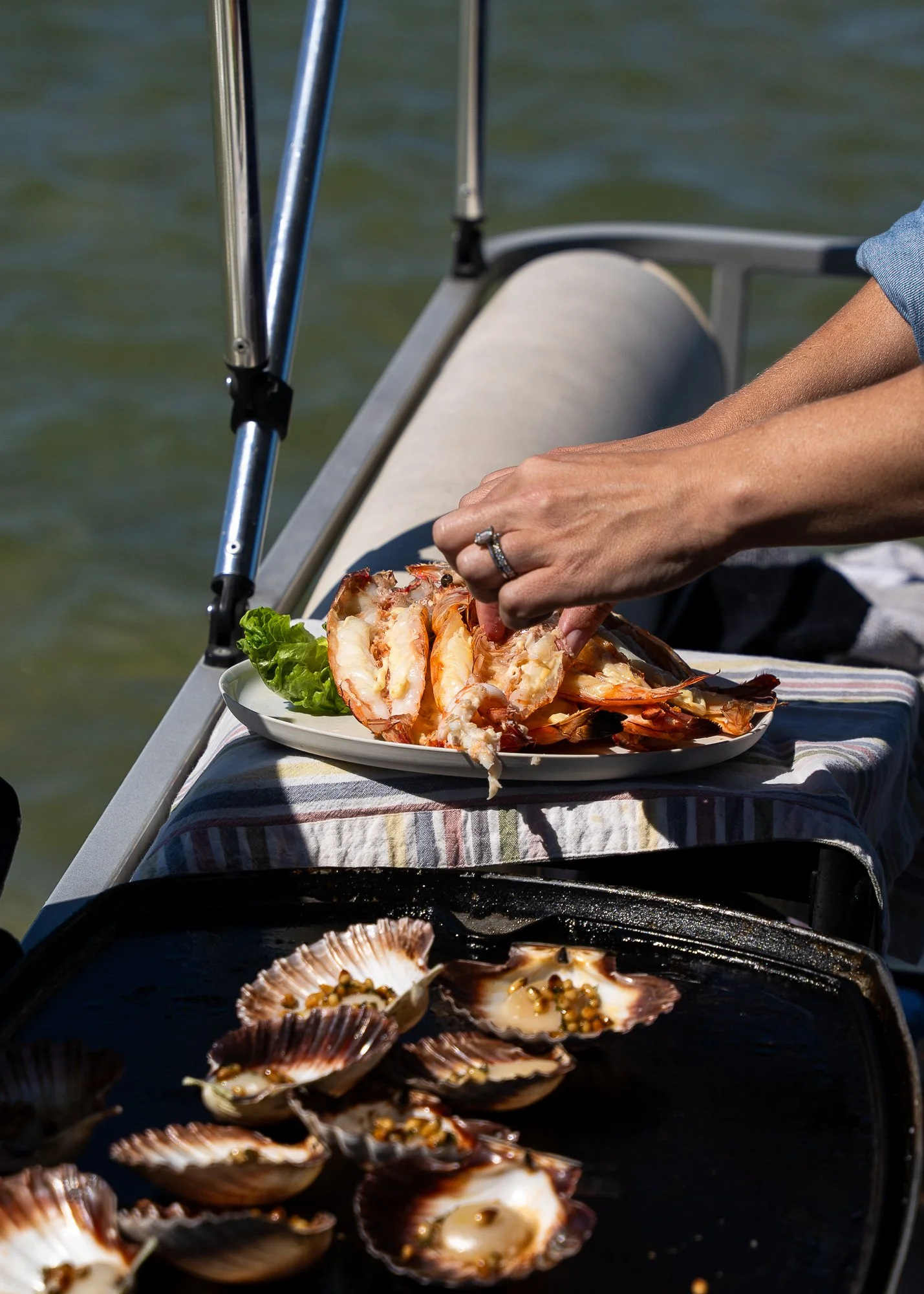 Person preparing shrimp and scallops on a boat.