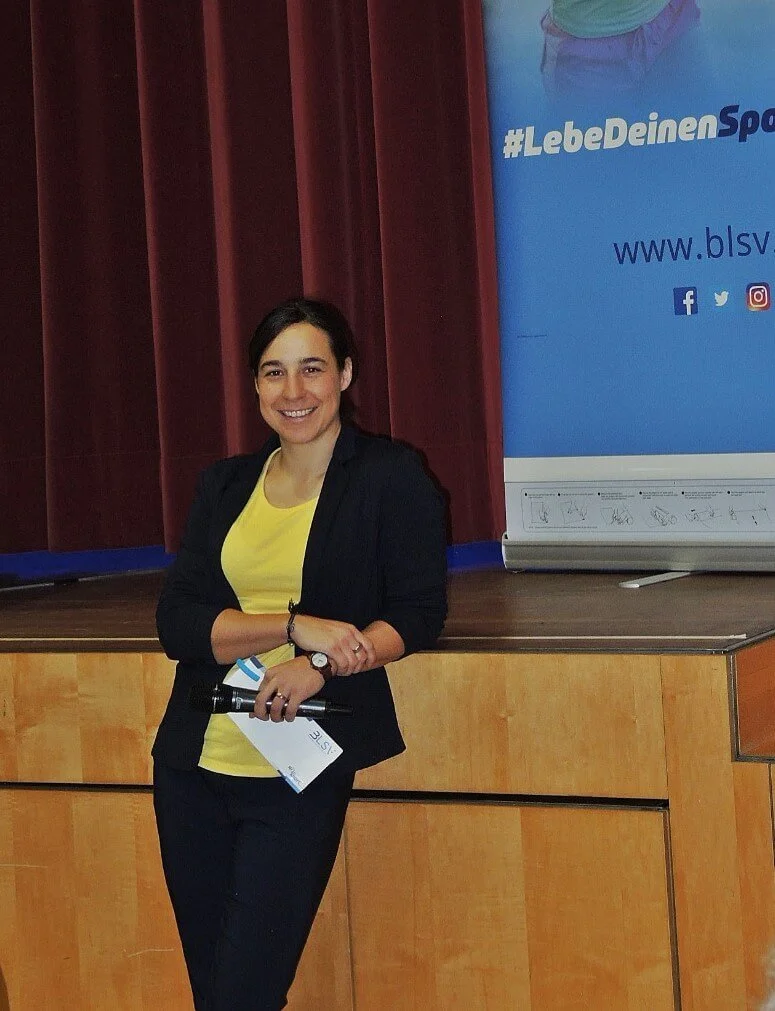 Janine Faaß steht vor der Bühne als sie eine Moderation für den bayerischen Landessportverband gemacht hat.