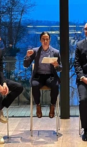 Janine Faaß sitzt in der Mitte eines Stuhlkreises und leitet die Podiumsdiskussion.