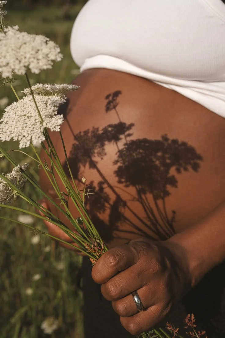Pregnant belly enjoying time in the sun holding flowers