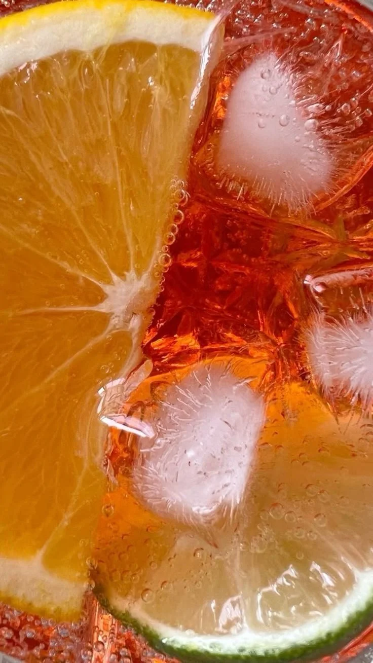 Close-up of lemon and lime slices with ice cubes in a fizzy drink.