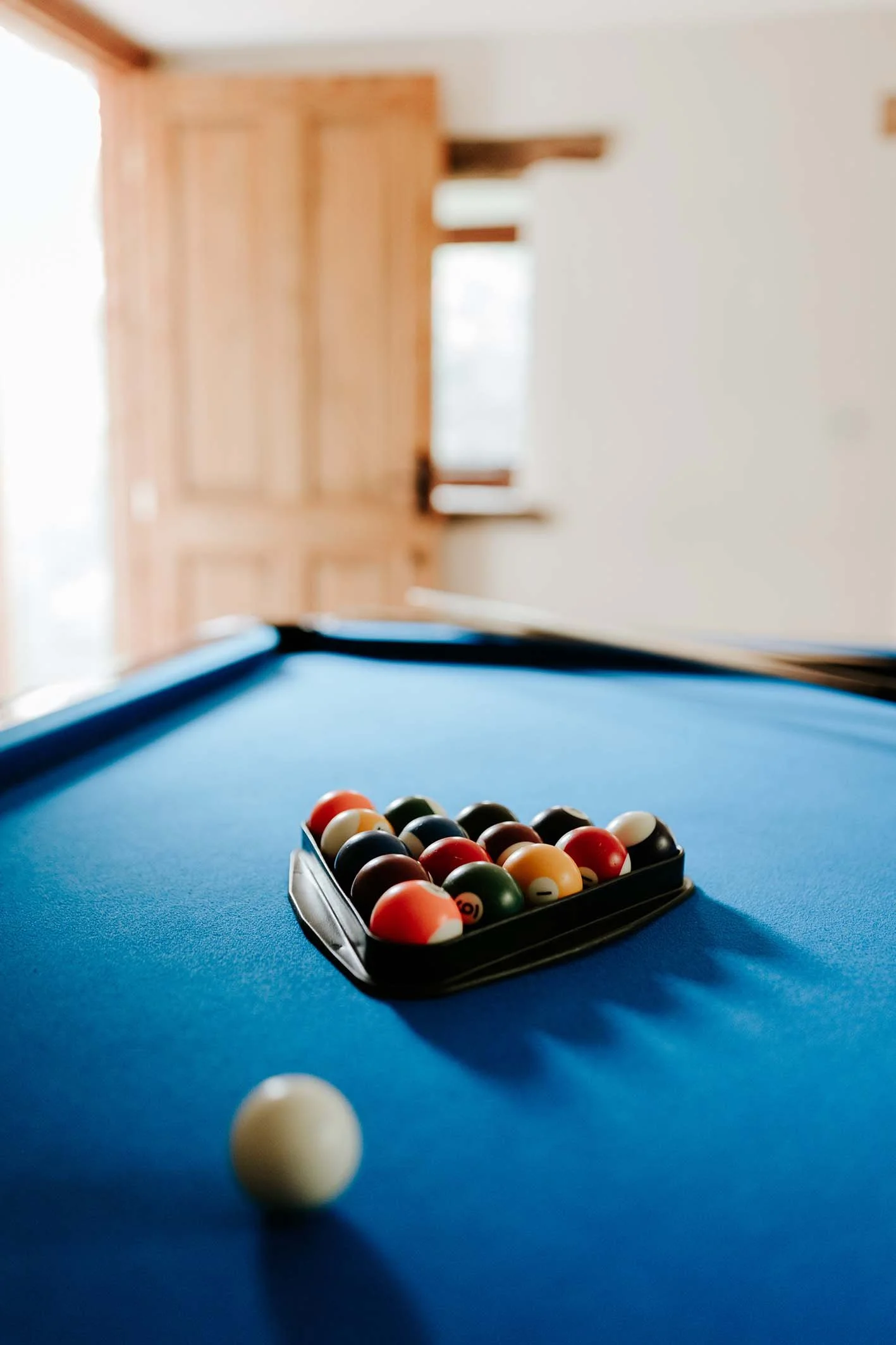 Billiard balls arranged on a pool table with a cue ball in the foreground.