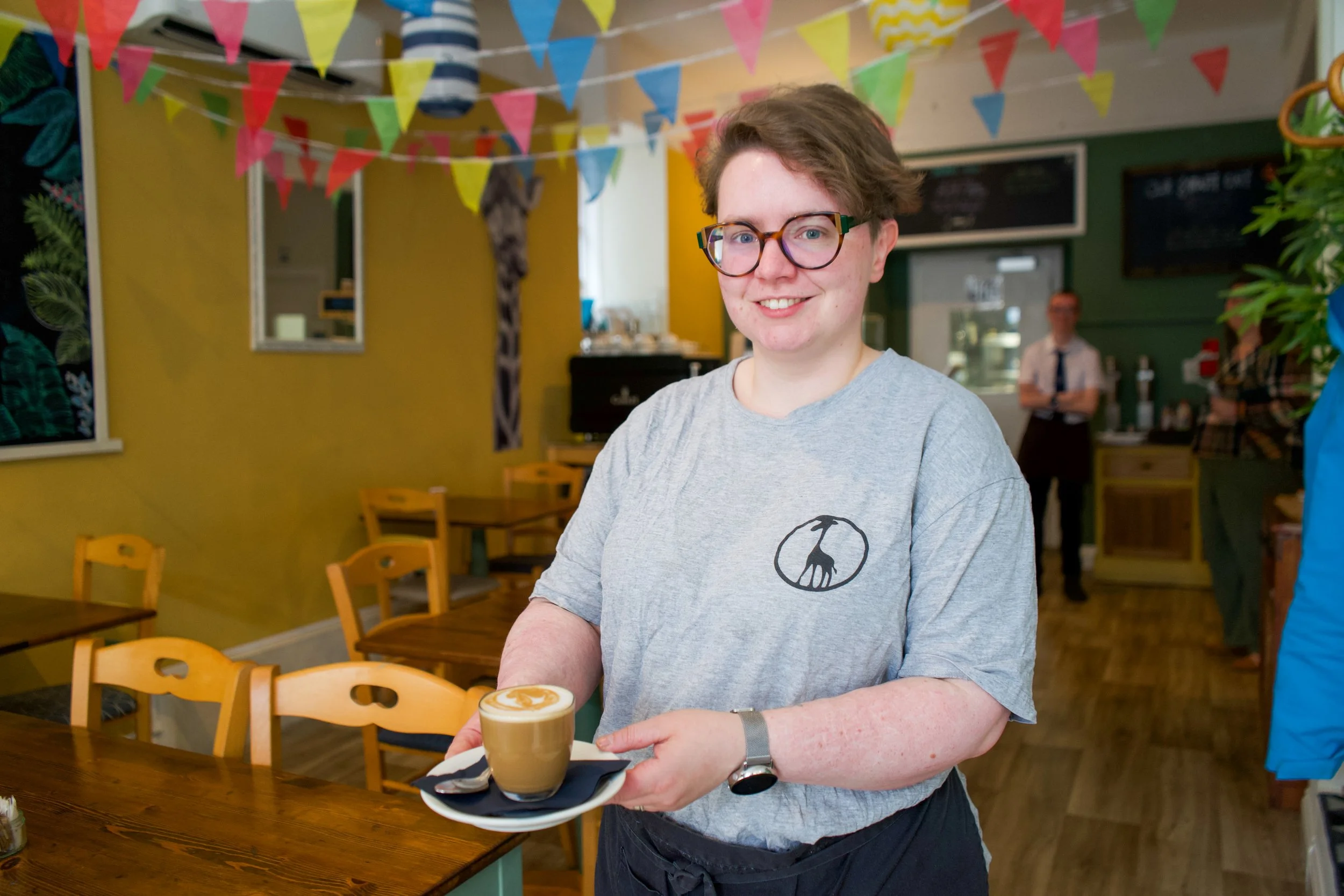 Giraffe Cafe team member holding a coffee