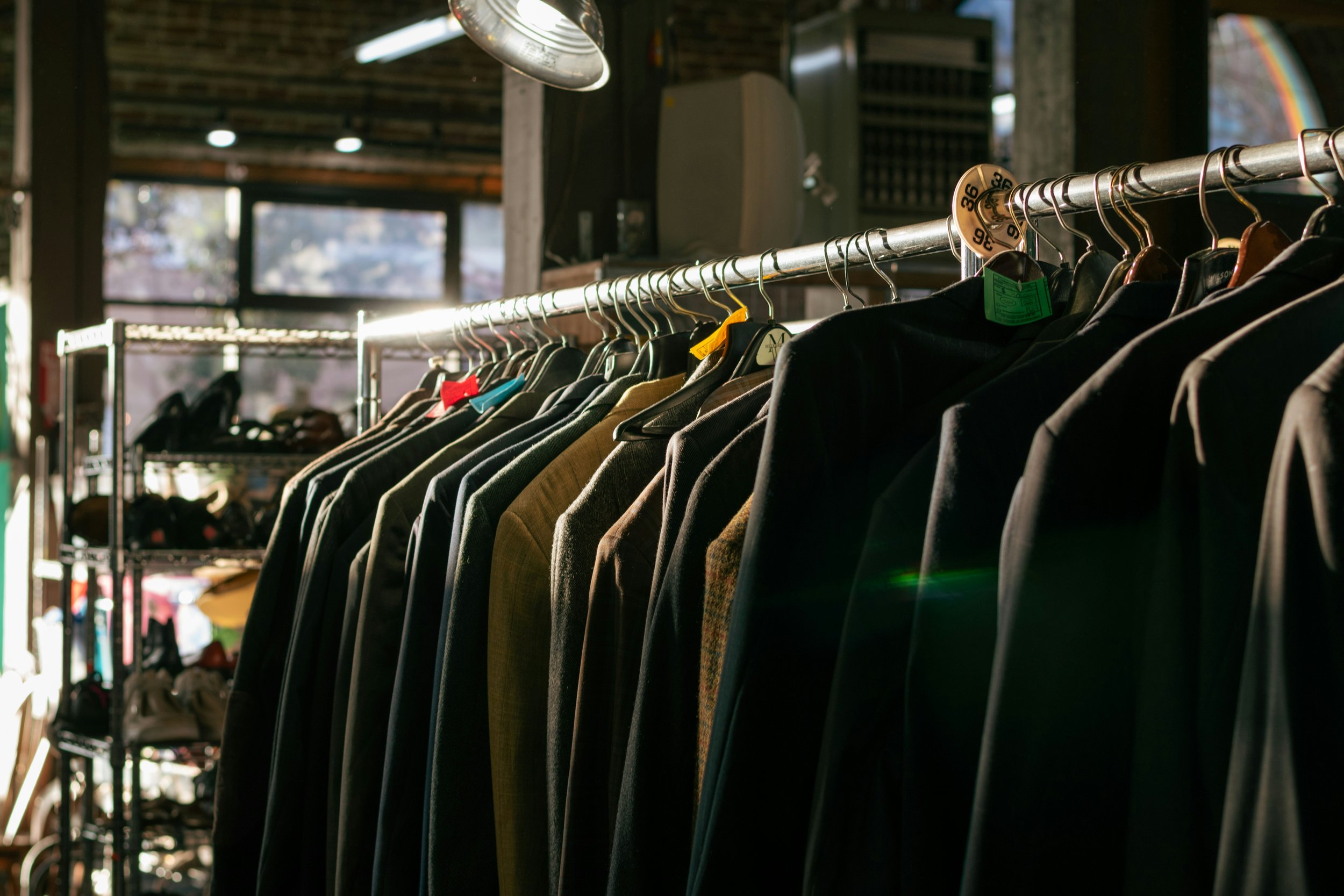Clothing hanging on a rack in a store or thrift shop.