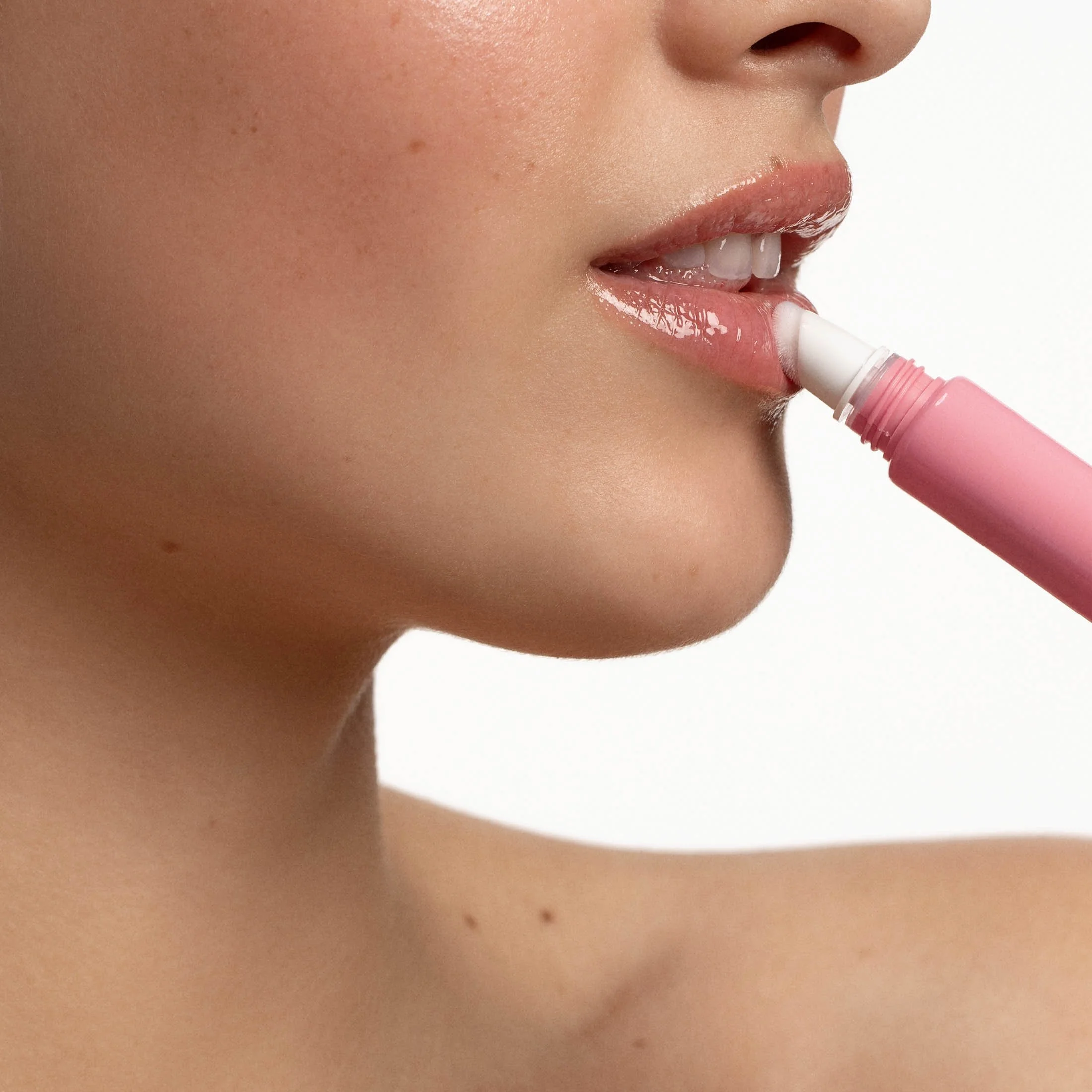 Close-up d'une femme appliquant du baume à lèvres à l'aide d'un ruban rose.