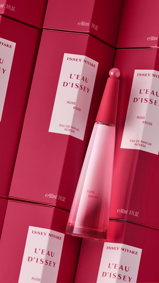 Une bouteille de parfum rose en forme conique avec un bouchon rond, entourée de boîtes roses de la même marque, portant l'inscription "L'EAU D'ISSEY" par ISSEY MIYAKE.