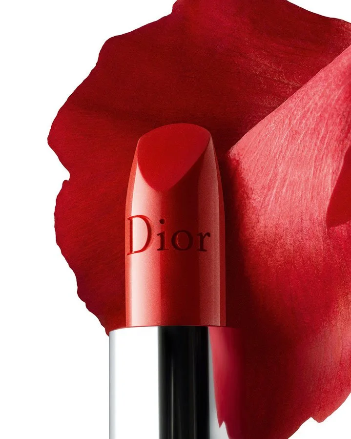 Un rouge à lèvres Dior devant une grande pétale de rose rouge.