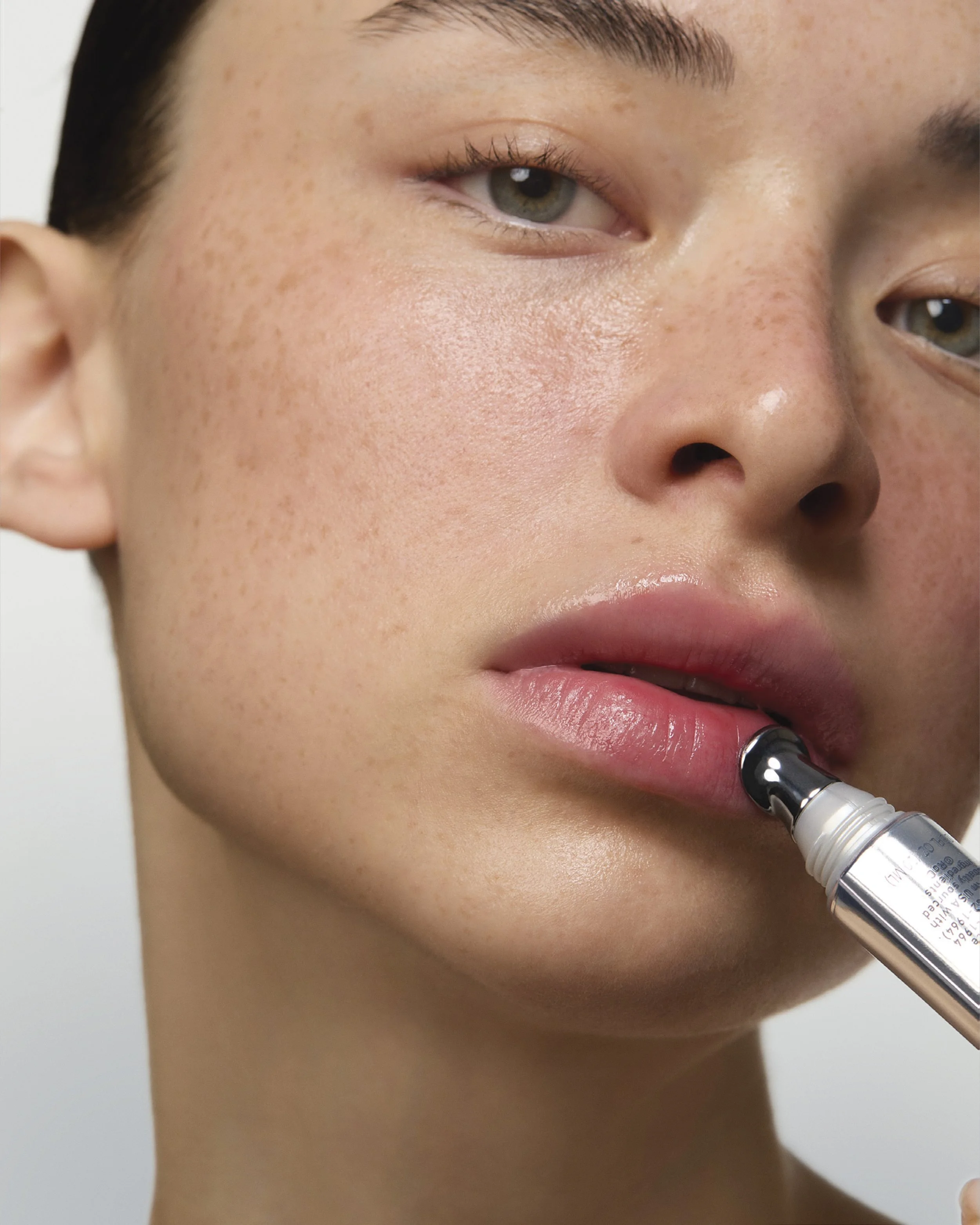 Une femme applique un sérum sur ses lèvres avec une pipette.