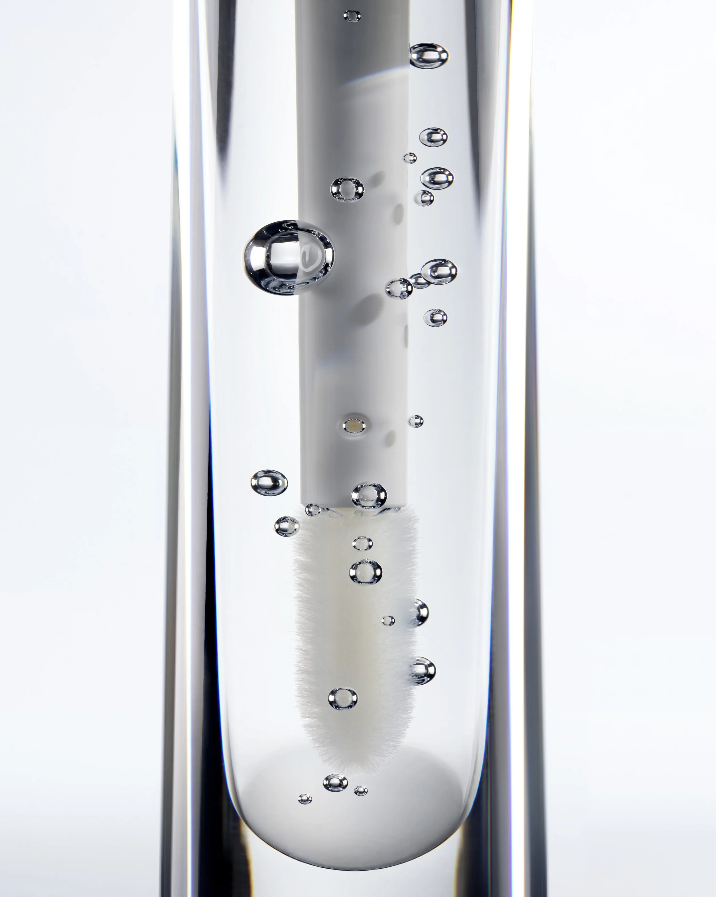 Un liquide transparent avec des bulles d'air à l'intérieur, probablement de l'eau gazeuse, dans un verre en pleine transparence.