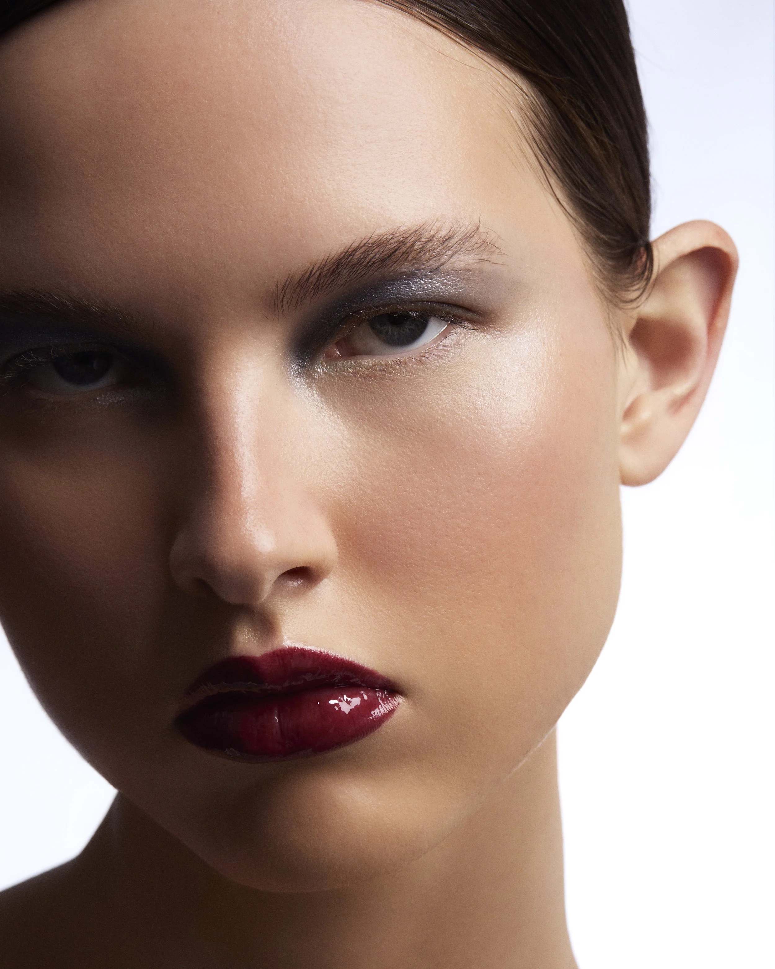 Un visage de femme avec maquillage sophistiqué, lèvres rouges et yeux avec maquillage foncé sur le coin extérieur.