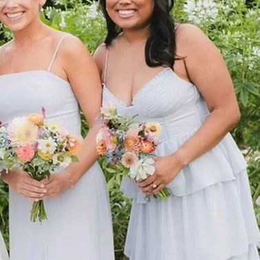 bridesmaids in coordinated soft blue dresses hold their petite and artistic bridesmaids bouquets.