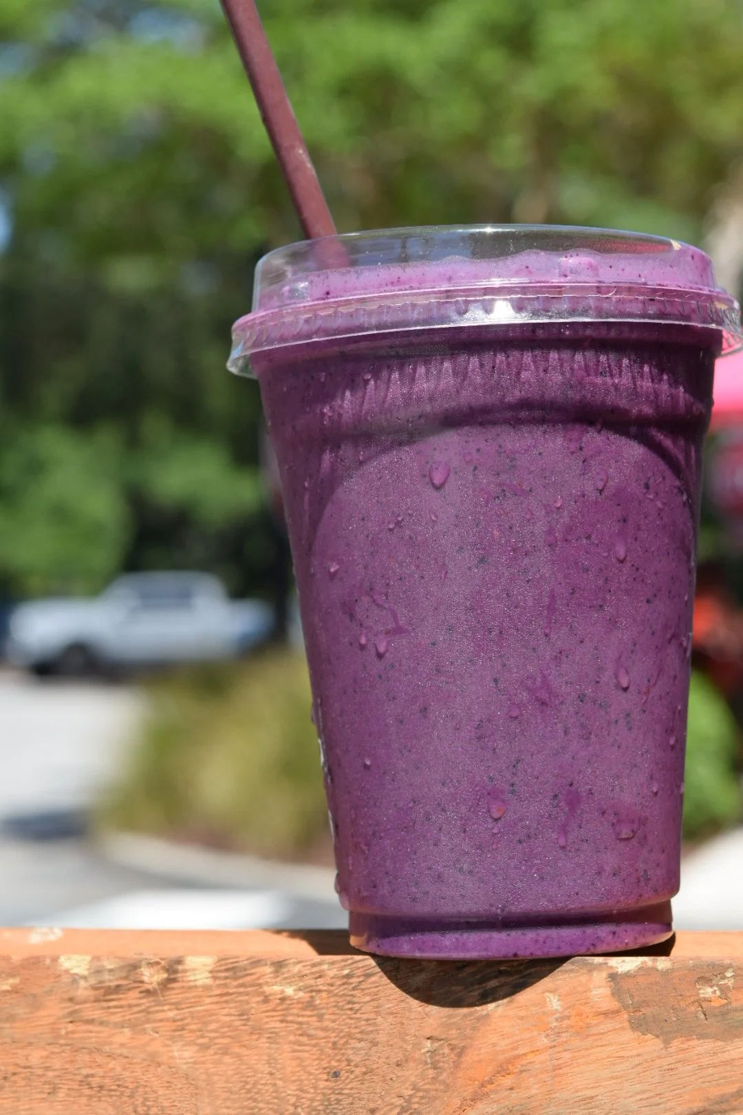 a purple smoothie in a clear plastic cup with condensation