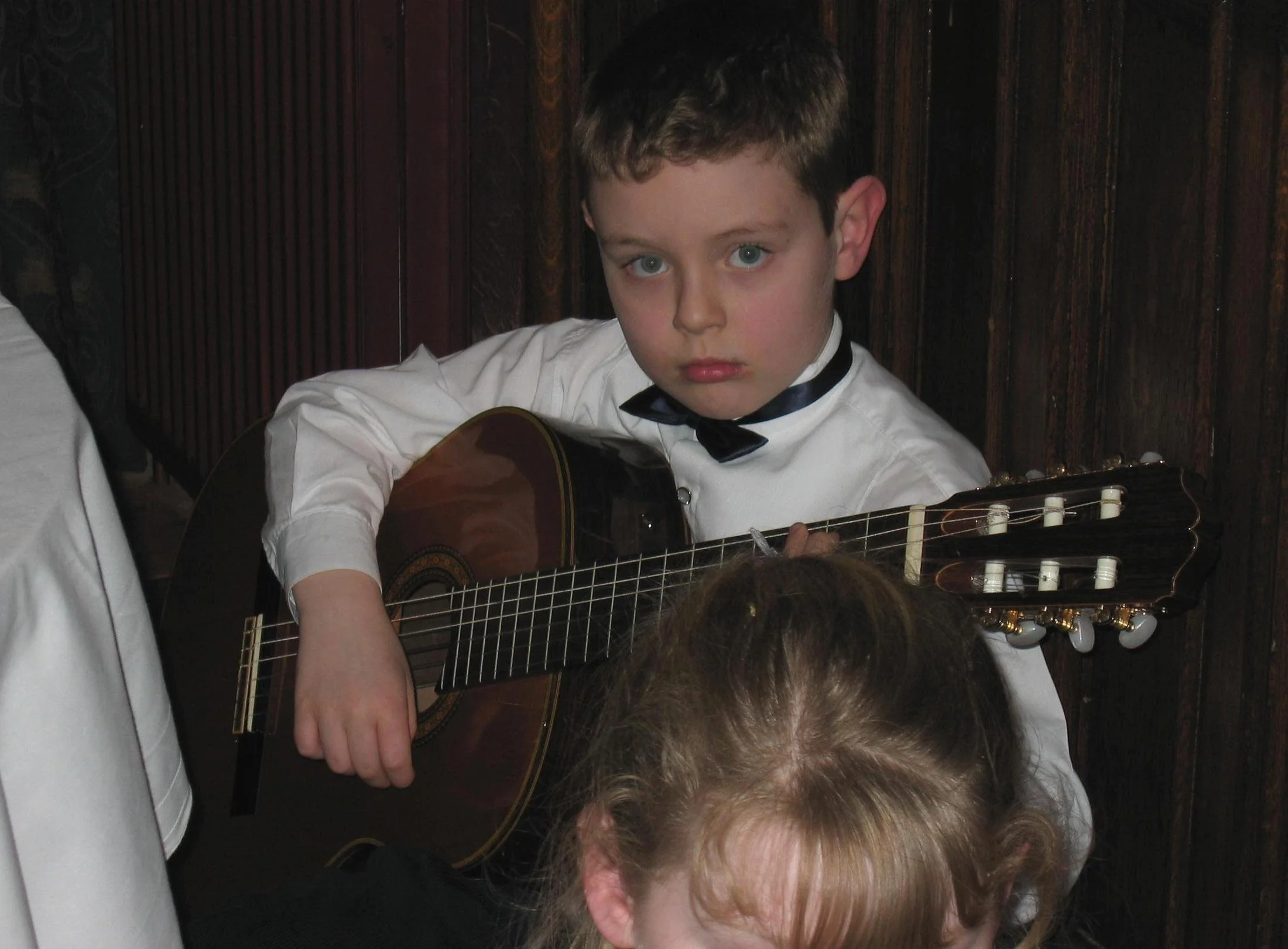 A child playing guitar looking at the camera