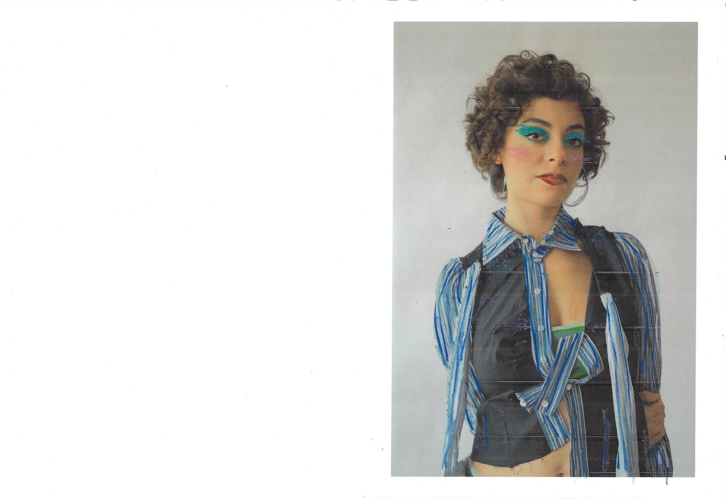 A woman with curly short hair, wearing bold blue eye makeup, earrings, and a striped shirt with blue and white stripes. She has a confident expression and is standing against a plain background.