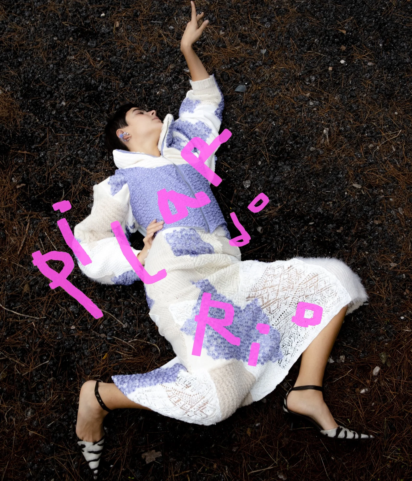 A woman lying on a bed of dark, wet leaves and pine needles, wearing a multicolored patchwork dress and zebra-striped heels with ankle straps, with pink handwritten words over the image.