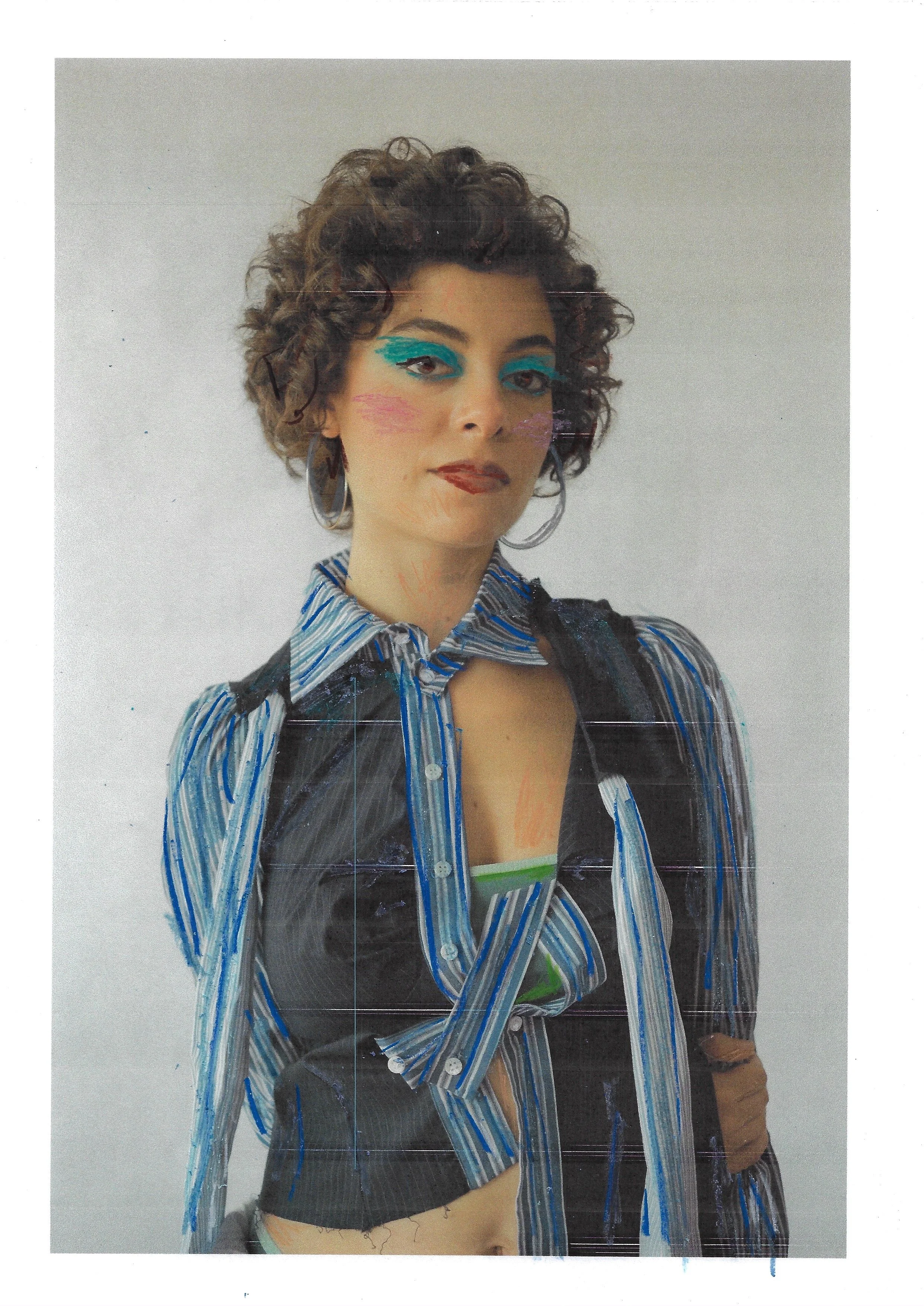 A woman with curly hair wearing bold blue eye makeup and a striped shirt with a black vest. She has large hoop earrings and is standing against a plain background.