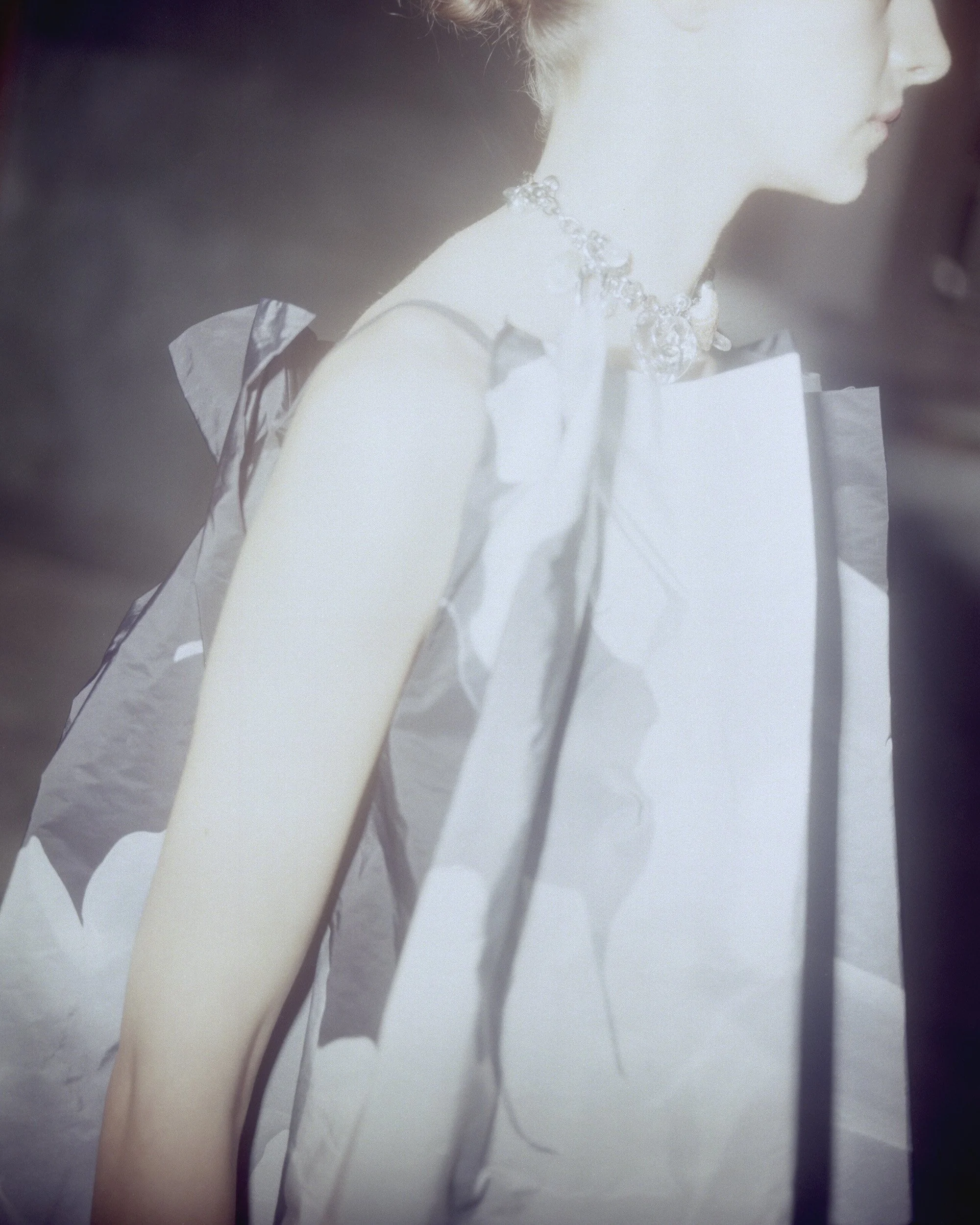 A woman wearing a white dress with black accents, adorned with a jewelry necklace.