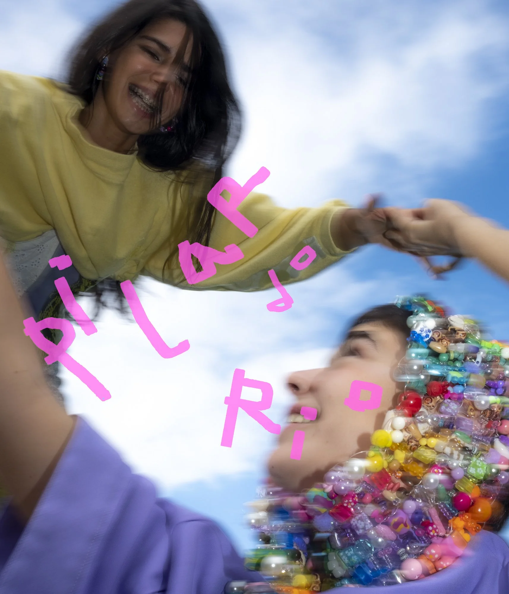 A woman in a yellow shirt reaching out and holding hands with a person with a face covered in colorful beads and small plastic toys. The sky is blue with some clouds.