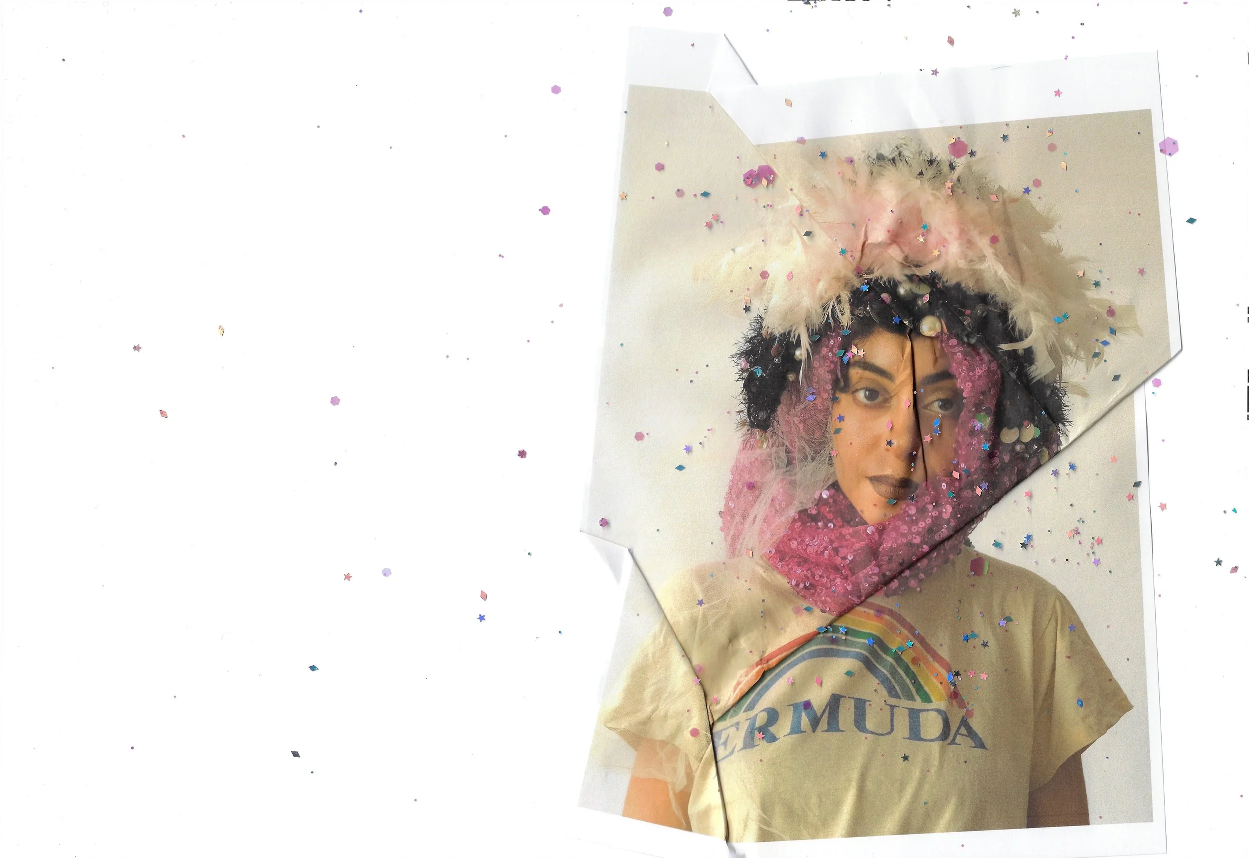 A person dressed in colorful, artistic costume with a feathered headpiece, dark makeup, and a tan shirt with the word 'BERMUDA' and a rainbow, surrounded by scattered confetti.