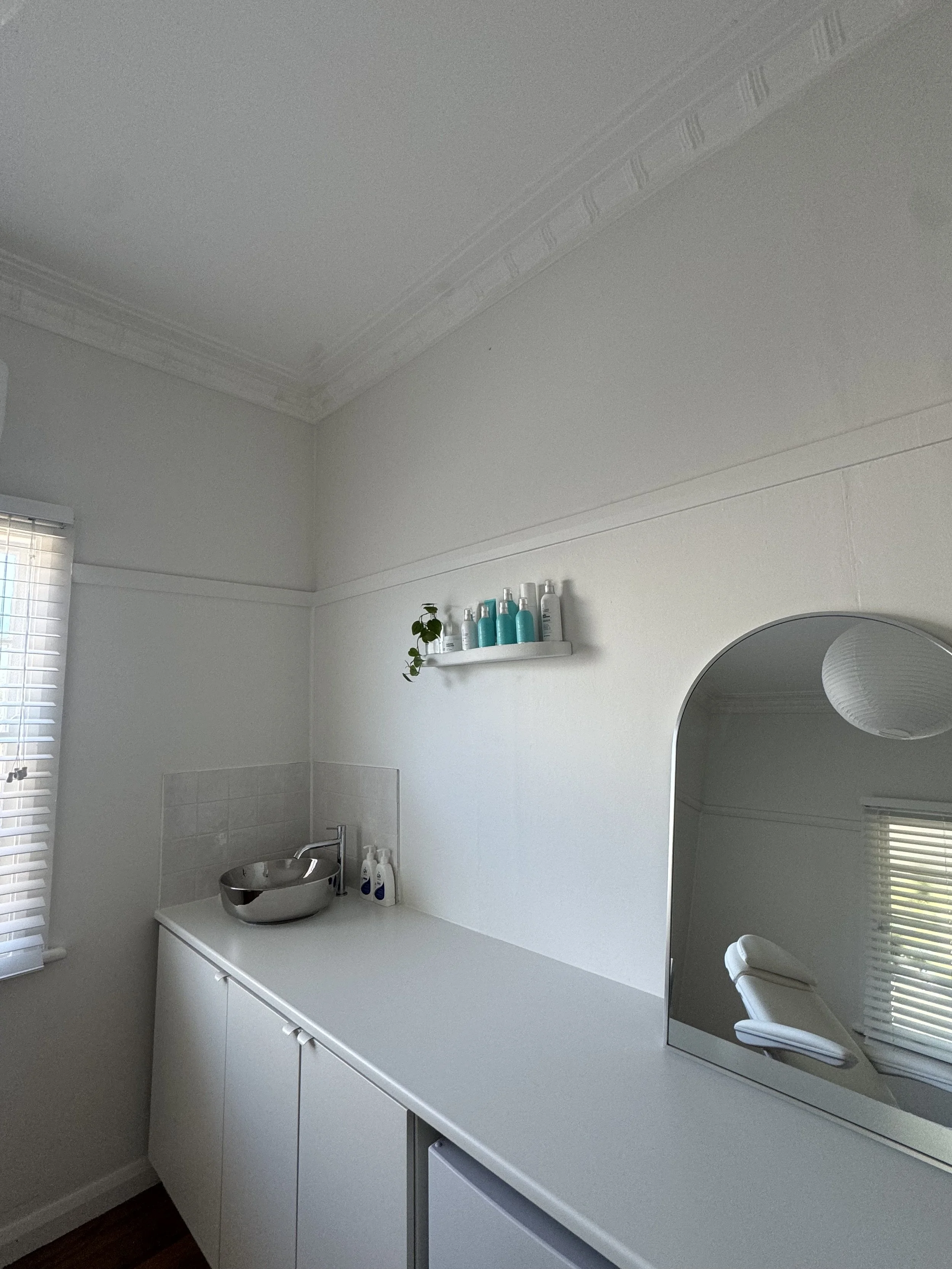 minimal aesthetic treatment room for cosmetic injectables with silver chrome sink natural light and skincare products