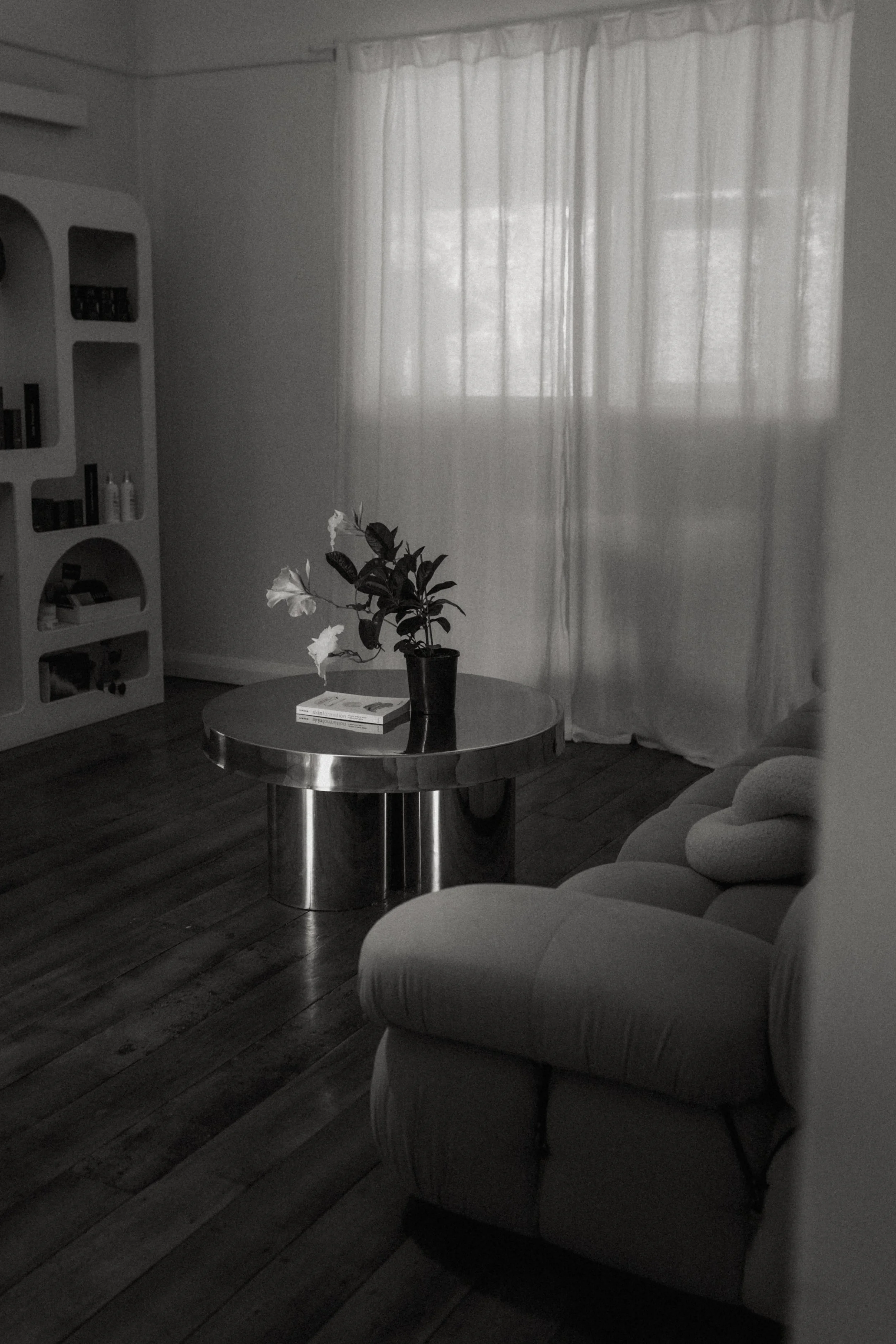 Skin clinic waiting room with treatment menu and skincare products on arched shelf
