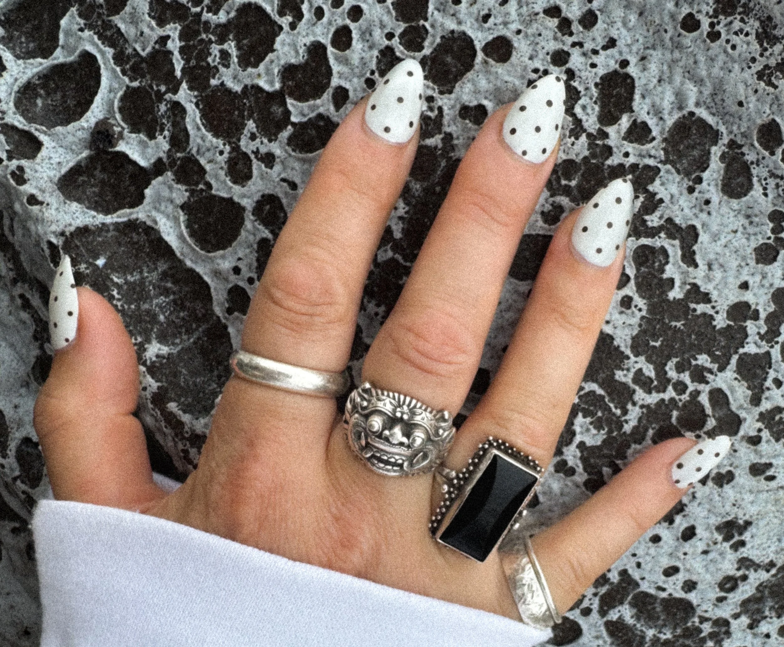 hand with cat eye polka dot nails and silver rings