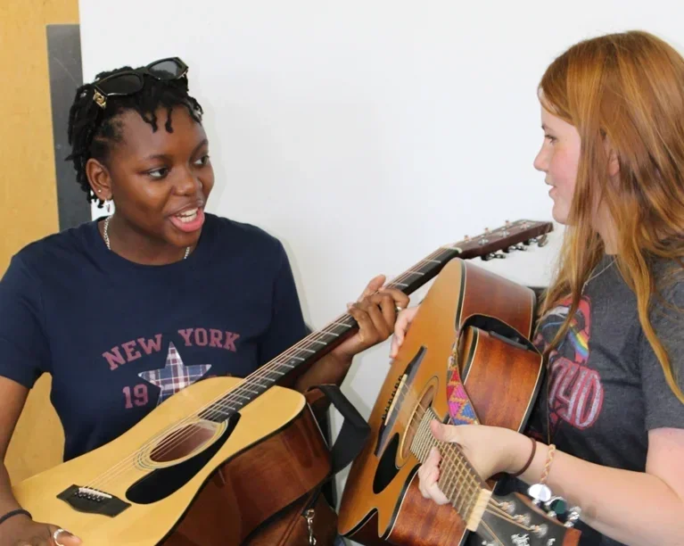 Photo of two participants of Song Academy writing on guitar