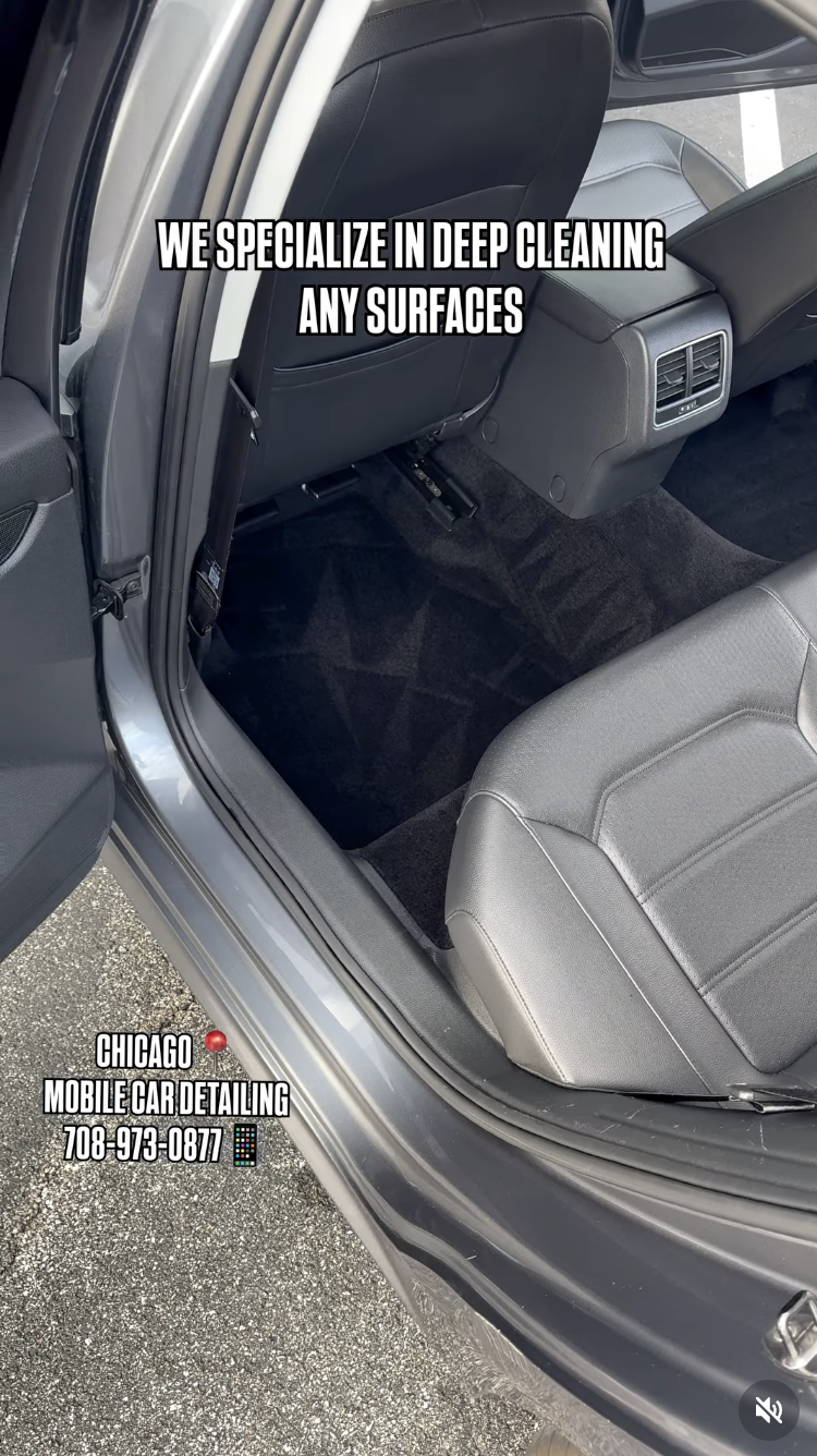 Interior of a car showing the backseat area with a clean black floor mat and a rear air vent. Text overlay advertising deep cleaning services for any surfaces and the contact information for a Chicago mobile car detailing service.