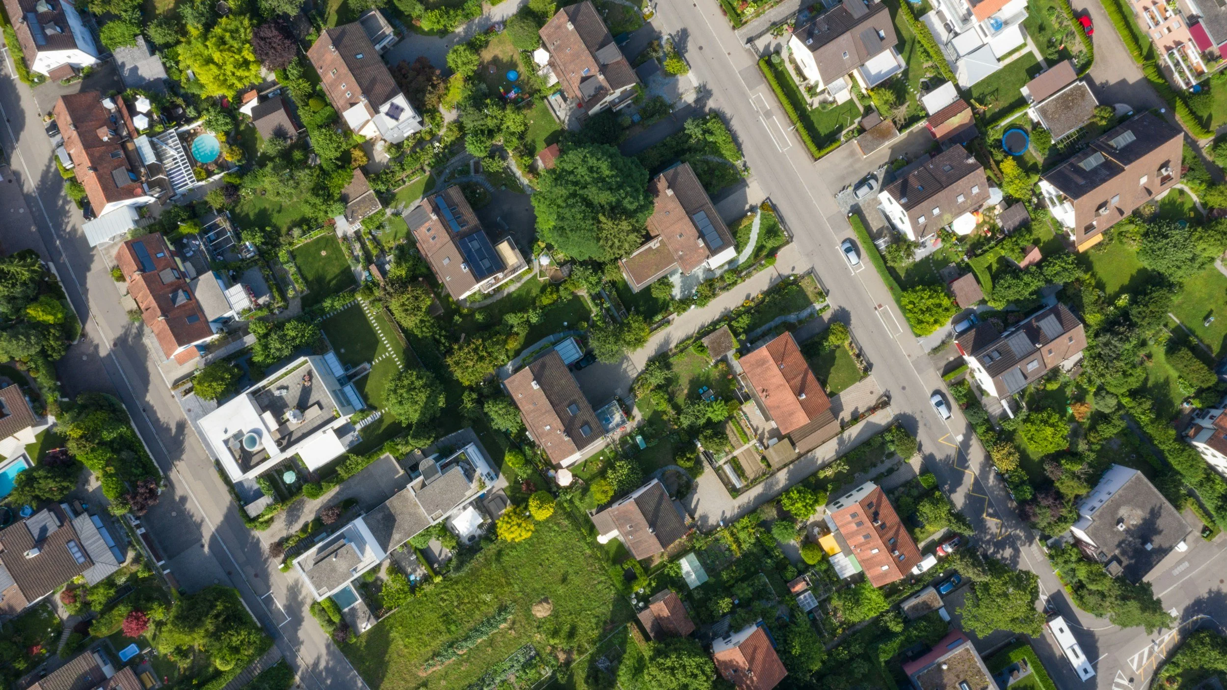 Residential neighbourhood, homes, aerial view or the roofs, street and green backyards. Real estate theme stock image.