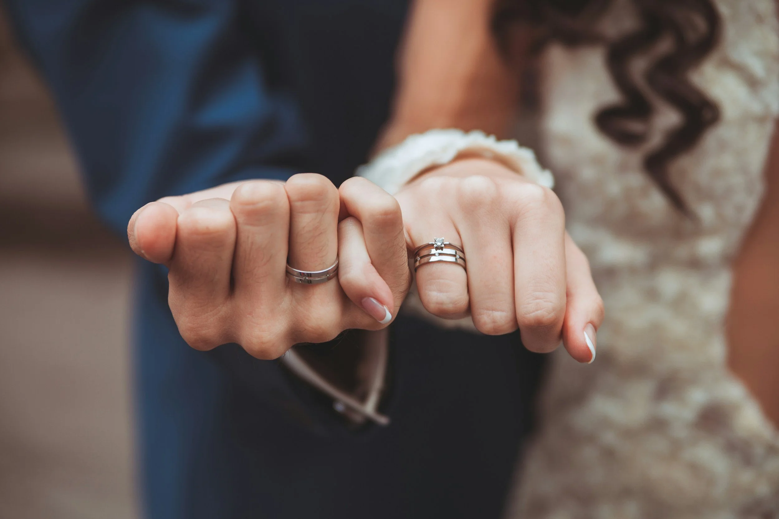 Marriage themed stock image, husband and wife holding hands by their pinky fingers, showing off their wedding rings at the same time.