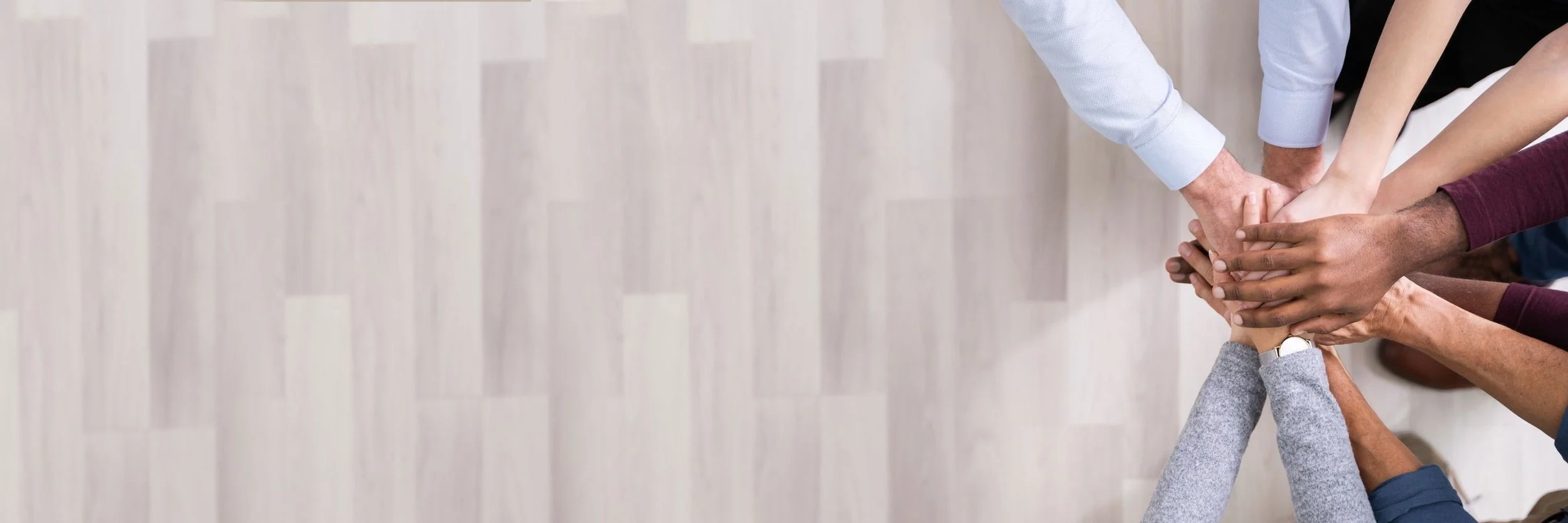 Diverse group of people putting their hands in the center as a team.