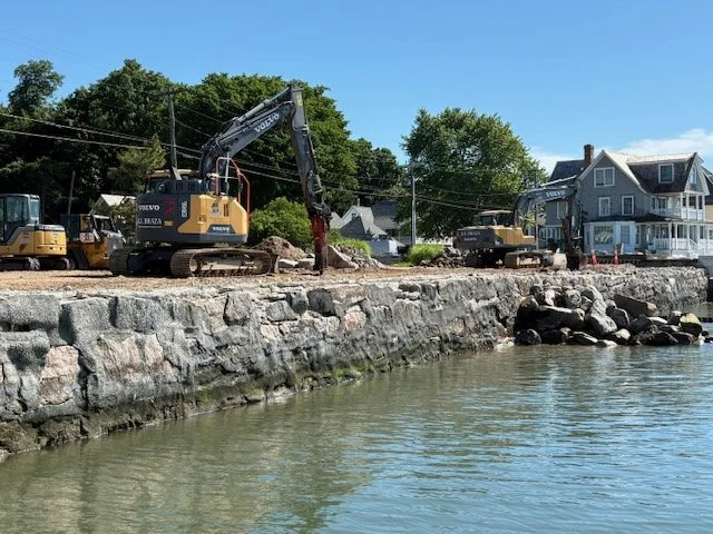 Tracked construction equipment working beside a stone-faced shoreline at Middle Beach in Madison, Connecticut