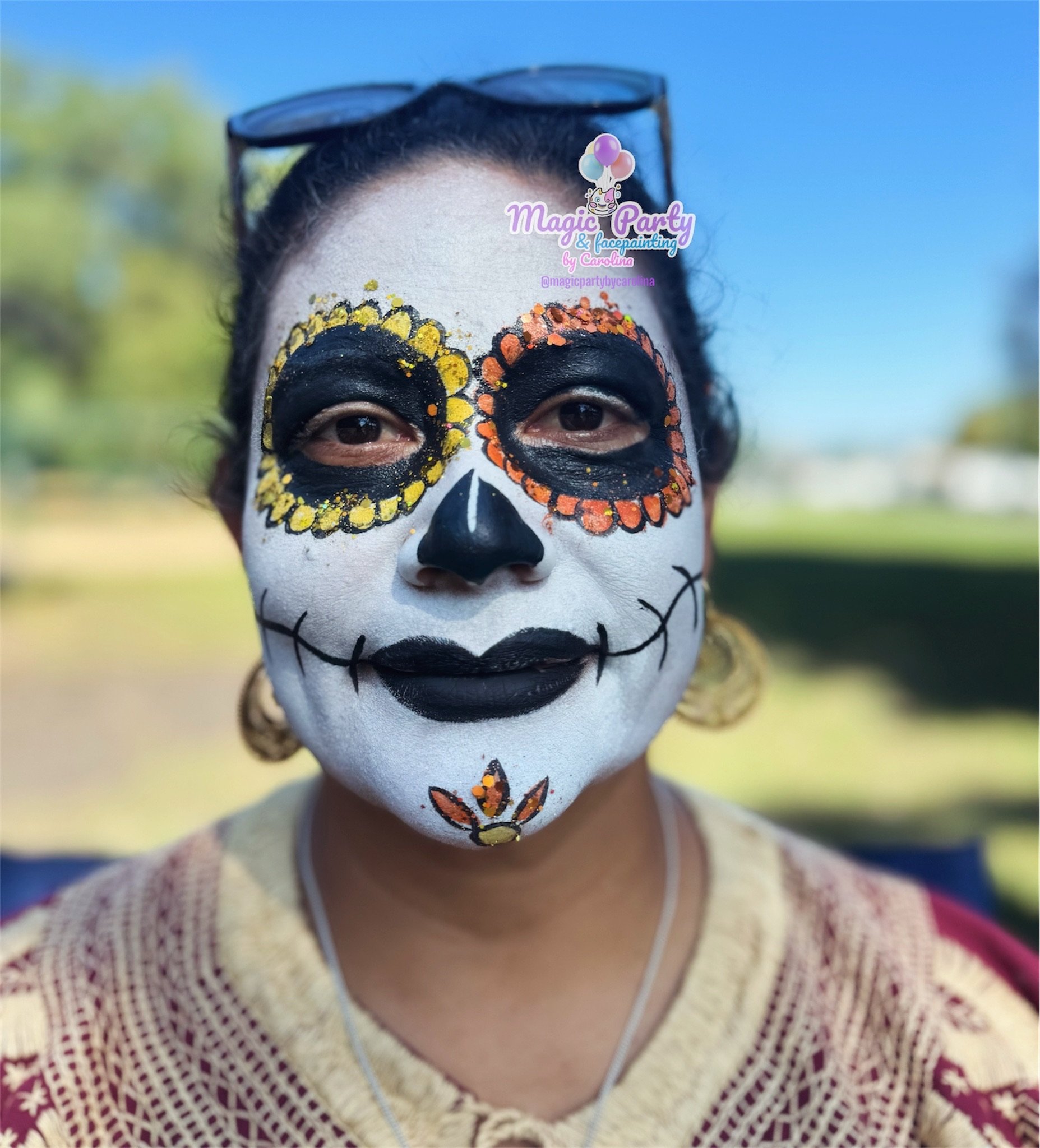 Person with Day of the Dead face paint in outdoor setting.