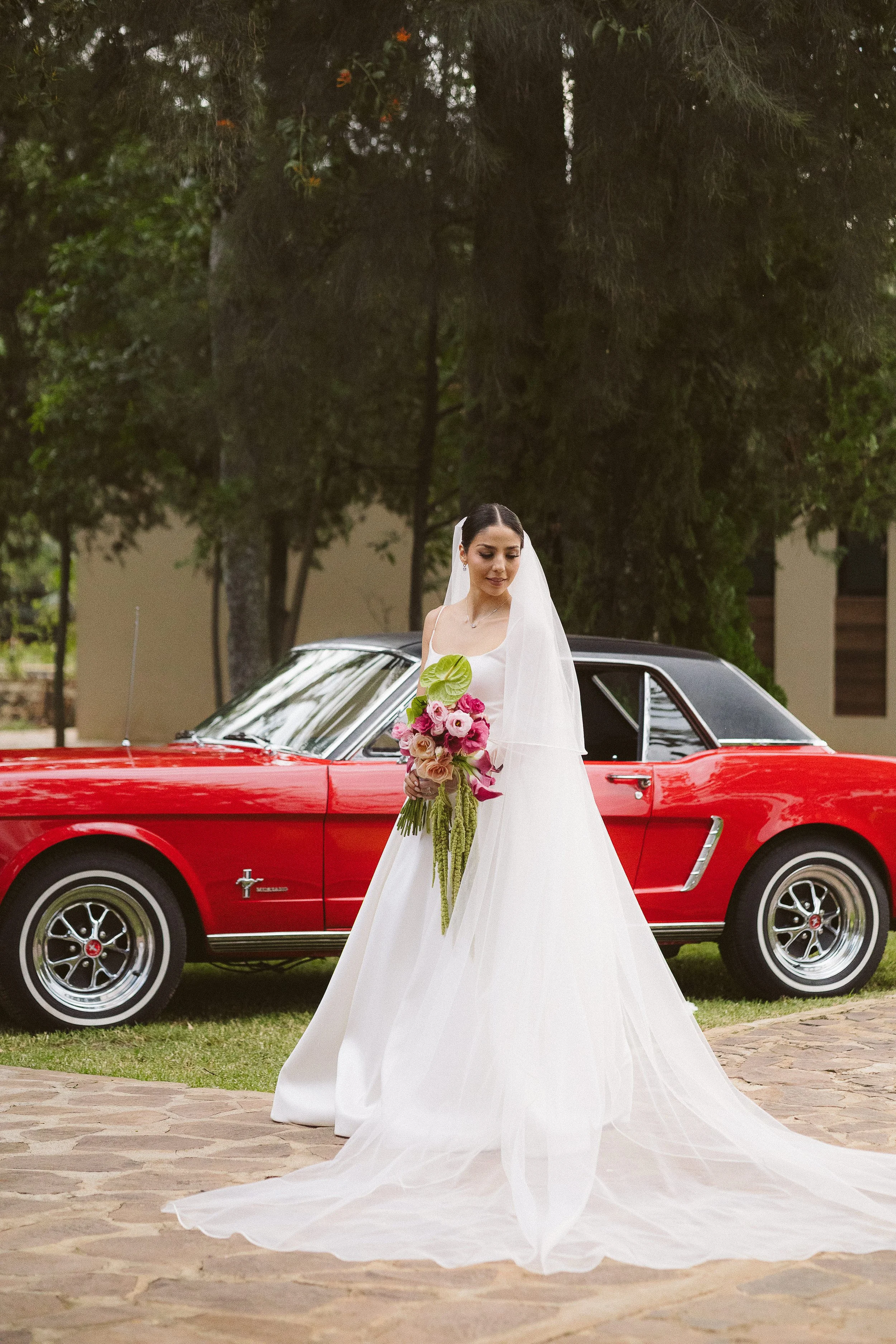 novia con bouquette frente a coche antiguo rojo