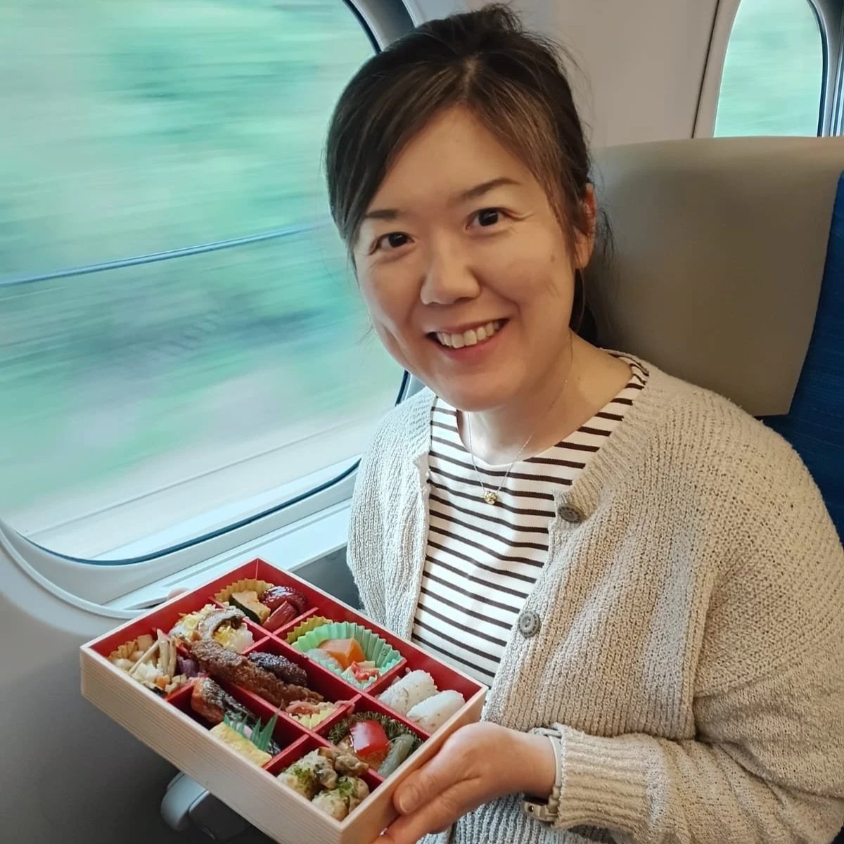 A woman sitting at a table holding a bowl of green matcha tea