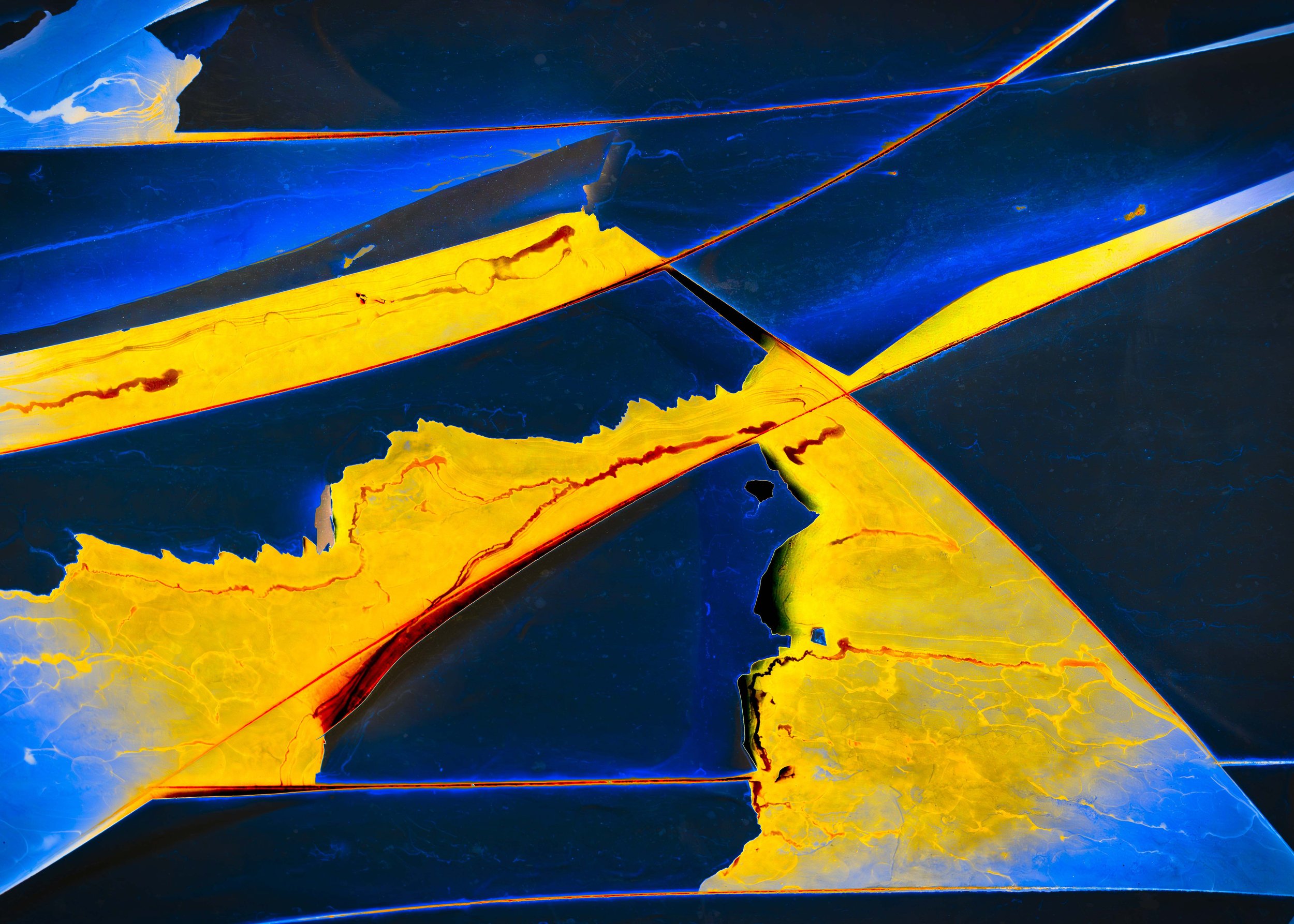 Close-up of a broken automotive windshield with cracked yellow and black glass pieces.