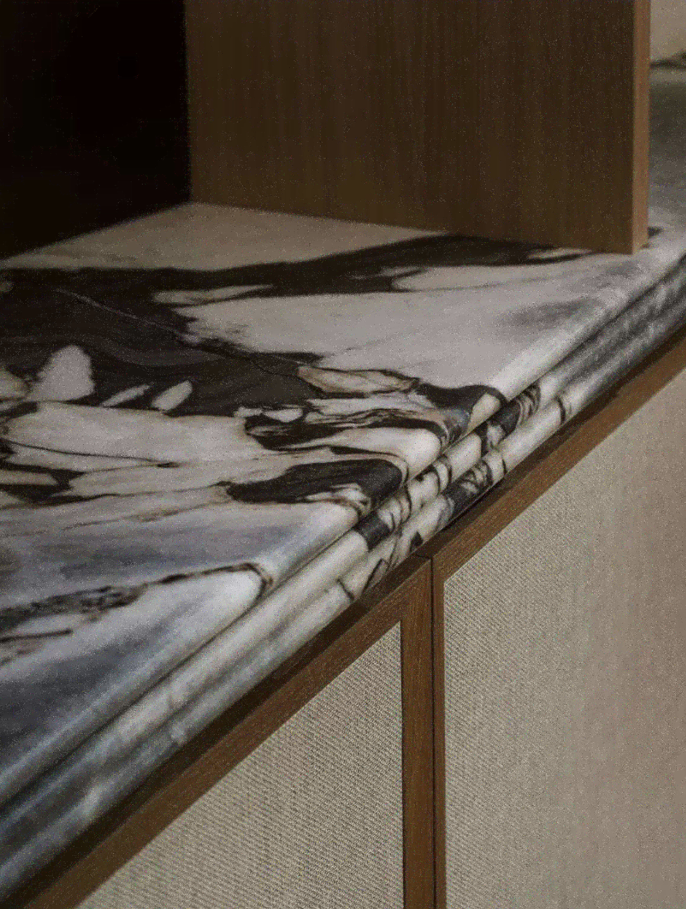 Close-up of a folded black and white marble-patterned cloth or paper on a wooden surface, with a textured beige carpet below.