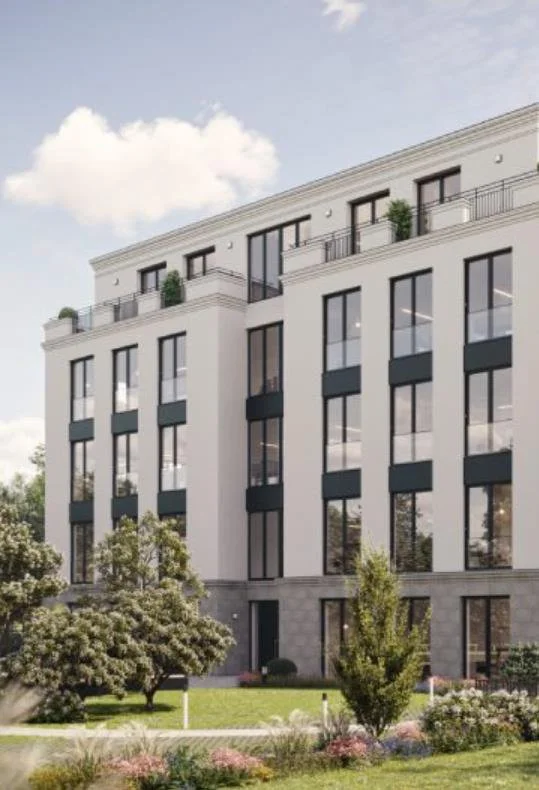Modern white multi-story residential building with large windows and balconies, surrounded by landscaped greenery and trees.