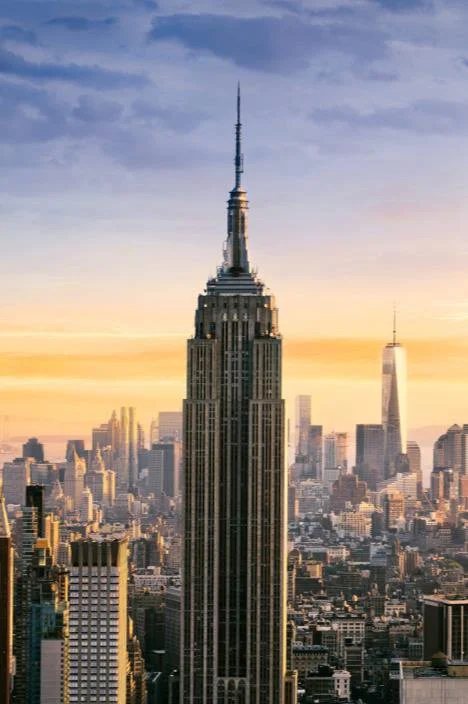 Skyline of New York City featuring the Empire State Building at sunset.