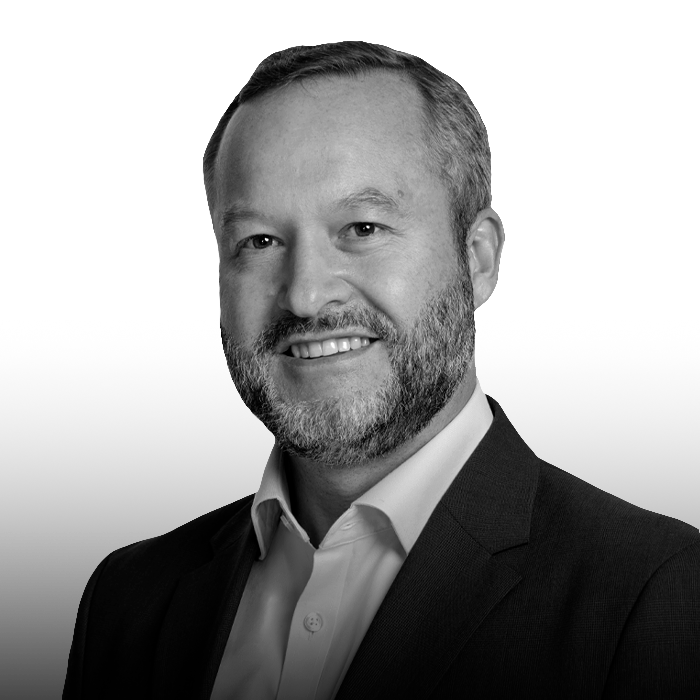 Black and white portrait of a middle-aged man with short dark hair, wearing a collared shirt, smiling softly, against a plain background.