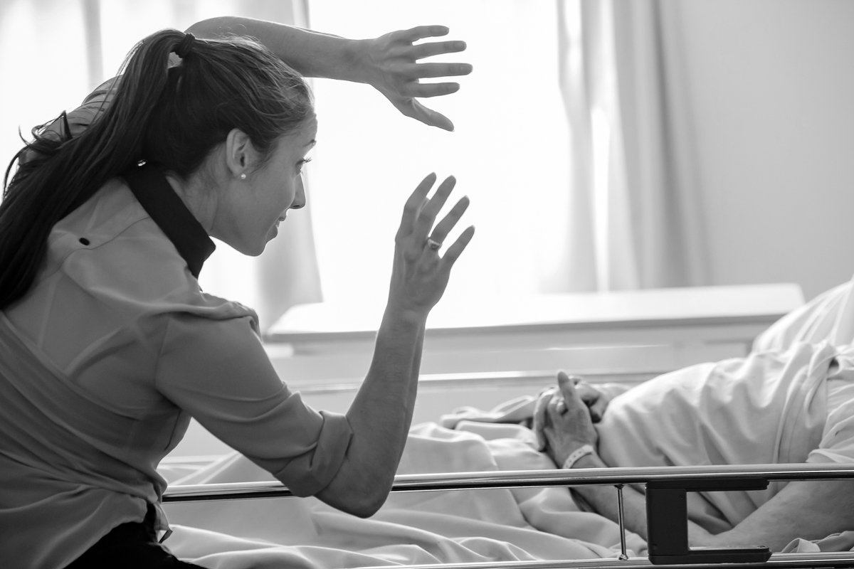 Une femme en colère ou stressée haute vers un patient allongé dans un lit d'hôpital, dans une pièce lumineuse