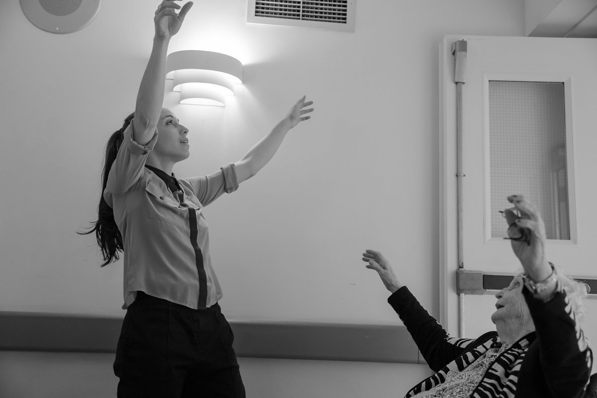 Une femme jeune et une femme âgée discutent dans une pièce, la femme jeune tendant la main vers le plafond.