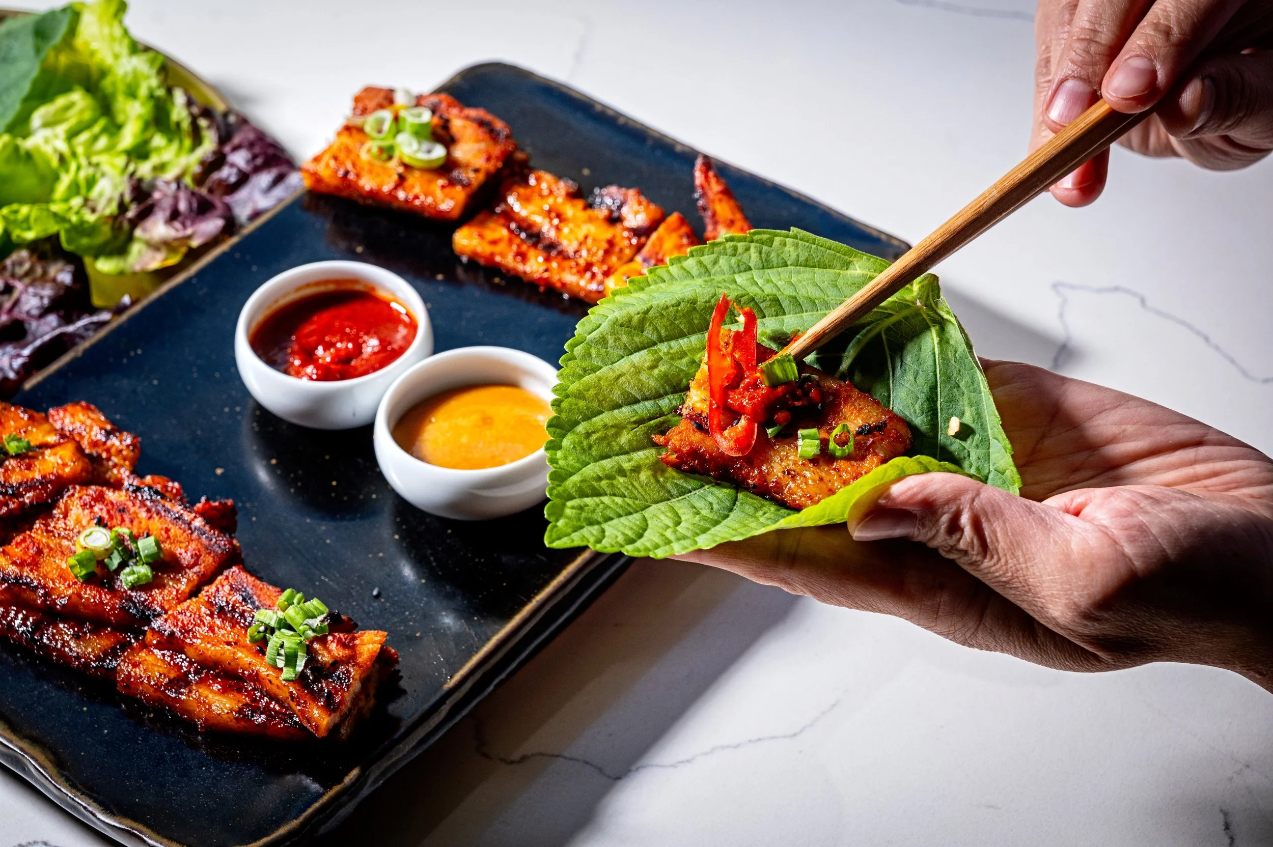 Grilled Samgyeopsal (Korean pork belly) with fresh lettuce, perilla wraps, and dipping sauces at Onggi in Washington DC. A classic Korean barbecue favorite perfect for sharing.