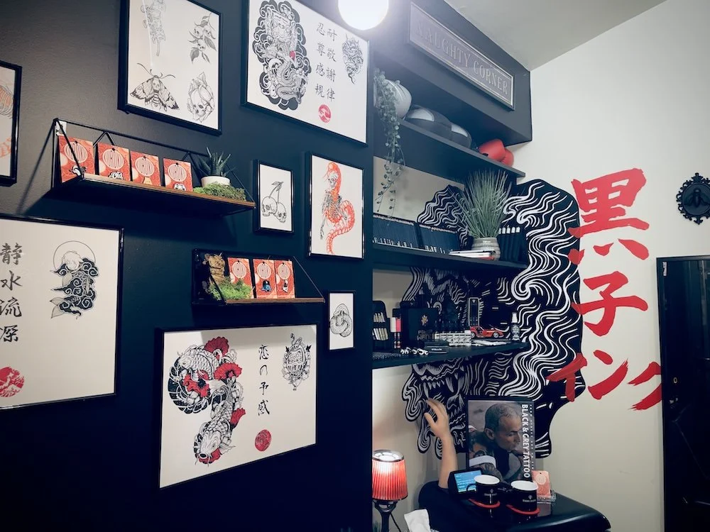 Kuroko Ink studio wall with framed artwork, shelving, and display decor