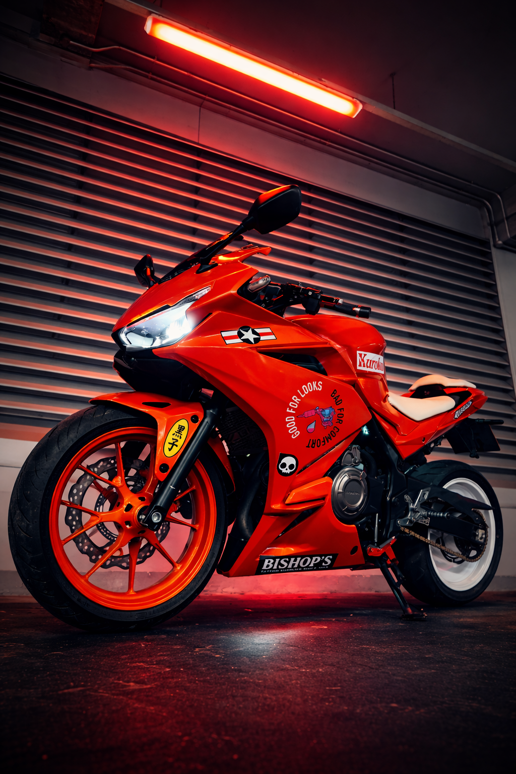 Red sport motorcycle with stickers, including a white skull and a circle that says 'Good for looks, Bad for comfort,' parked in front of a metallic wall with red lighting