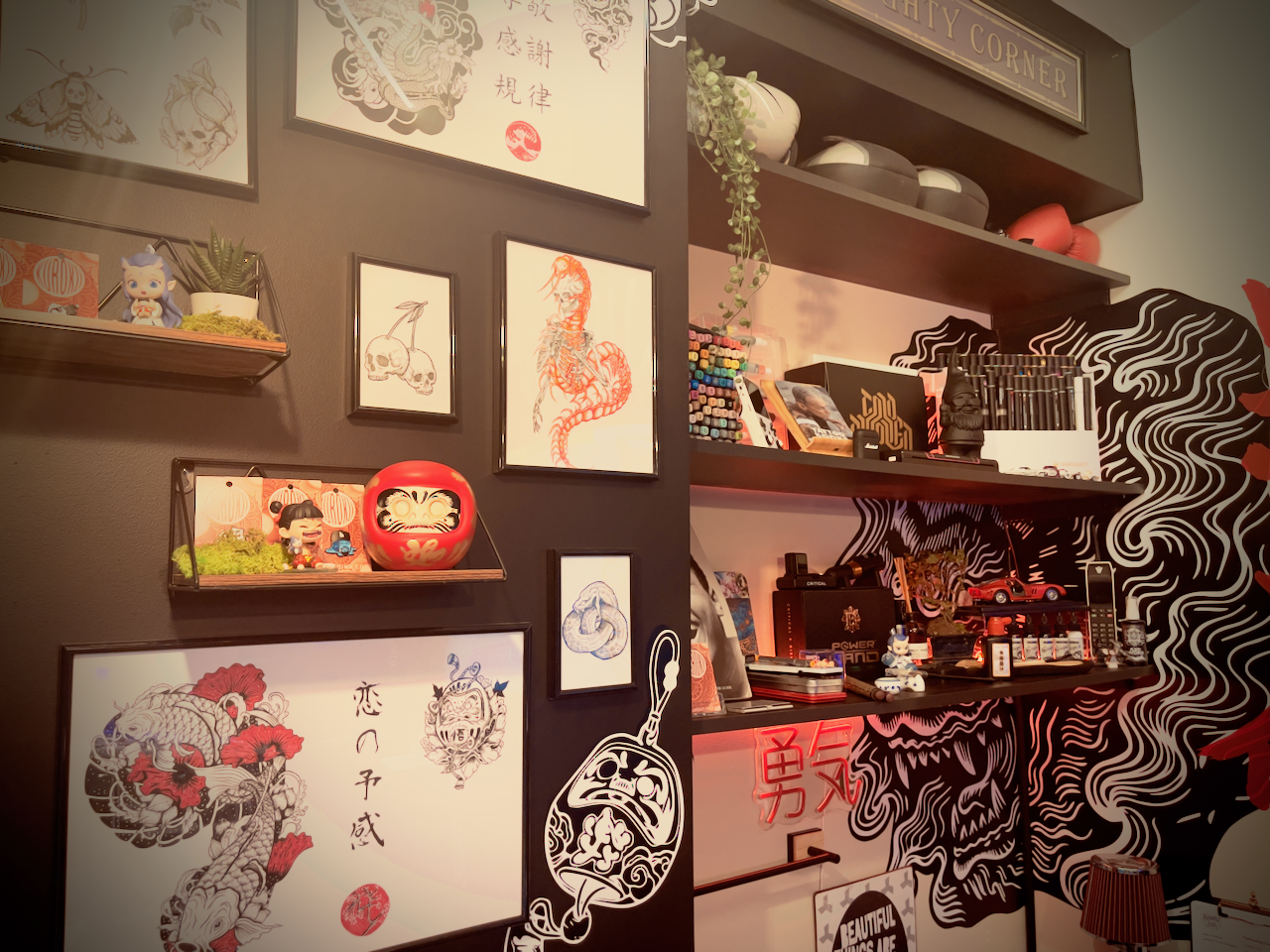 Studio wall with framed flash, Japanese artwork, and display shelving