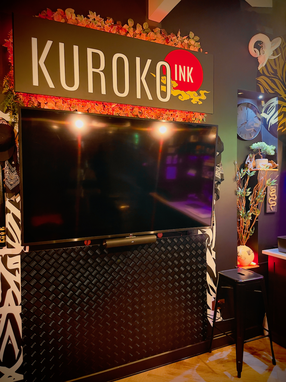 Kuroko Ink studio interior with wall-mounted TV and illuminated studio sign