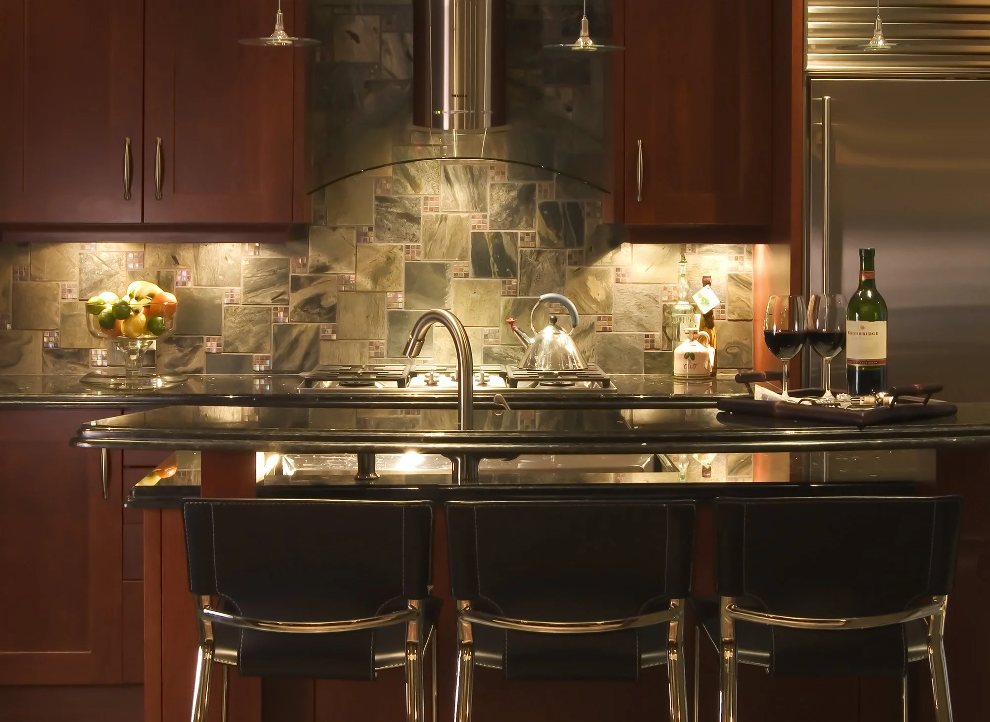 Shiny chrome kitchen with island and black leather seats