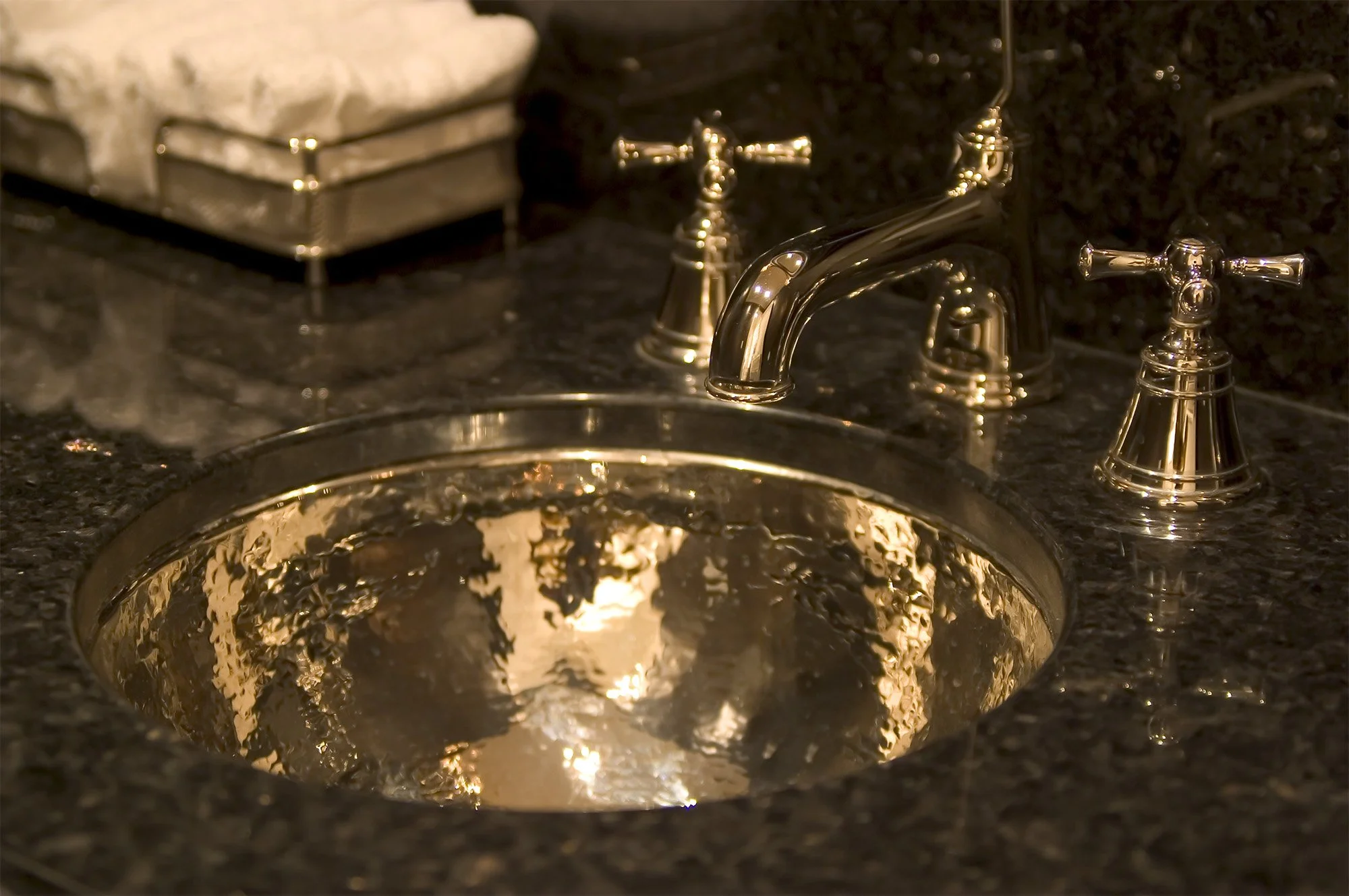 Black granite counter and hammered metal sink in bathroom