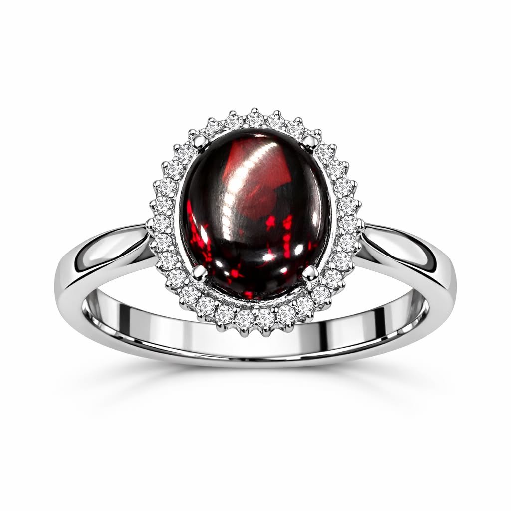 A silver ring with a large black and red gemstone surrounded by small clear stones, set against a white background.